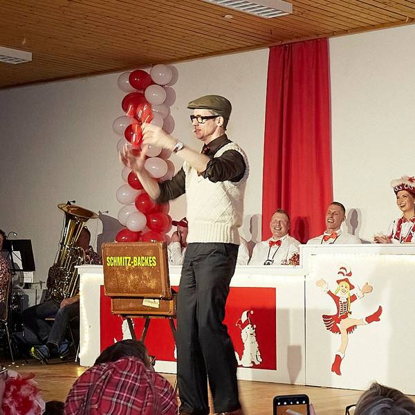 Auf der Nettersheimer Bühne produziert der Zauberer Schmitz-Backes eine Ballonfigur. Sein Publikum lacht.