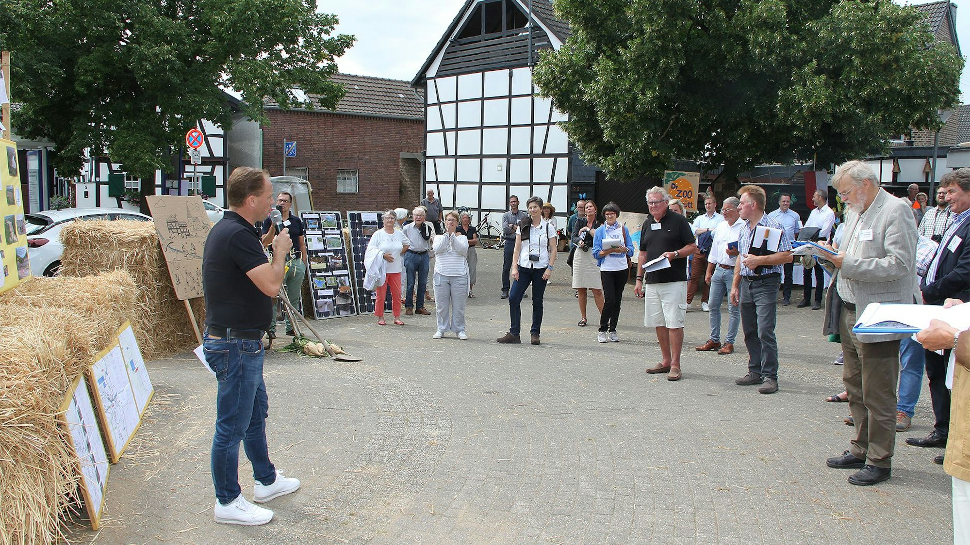 Das Bild zeigt die Kommission von „Unser Dorf in Zukunft“ in Schweinheim. Landwirt Stephan Brock (links) informiert auf dem Dorfplatz.