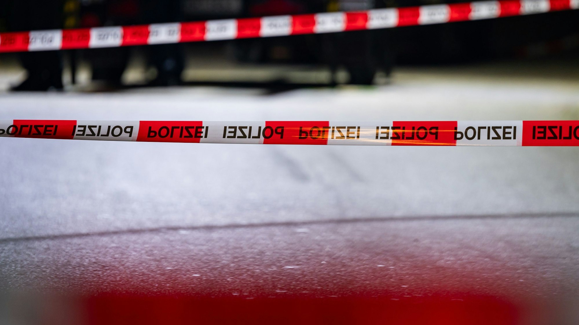 Ein Tatort ist mit einem Flatterband abgesperrt. Auf dem rot-weißen Band ist mehrfach die Aufschrift „Polizei“ zu lesen. (Symbolbild)
