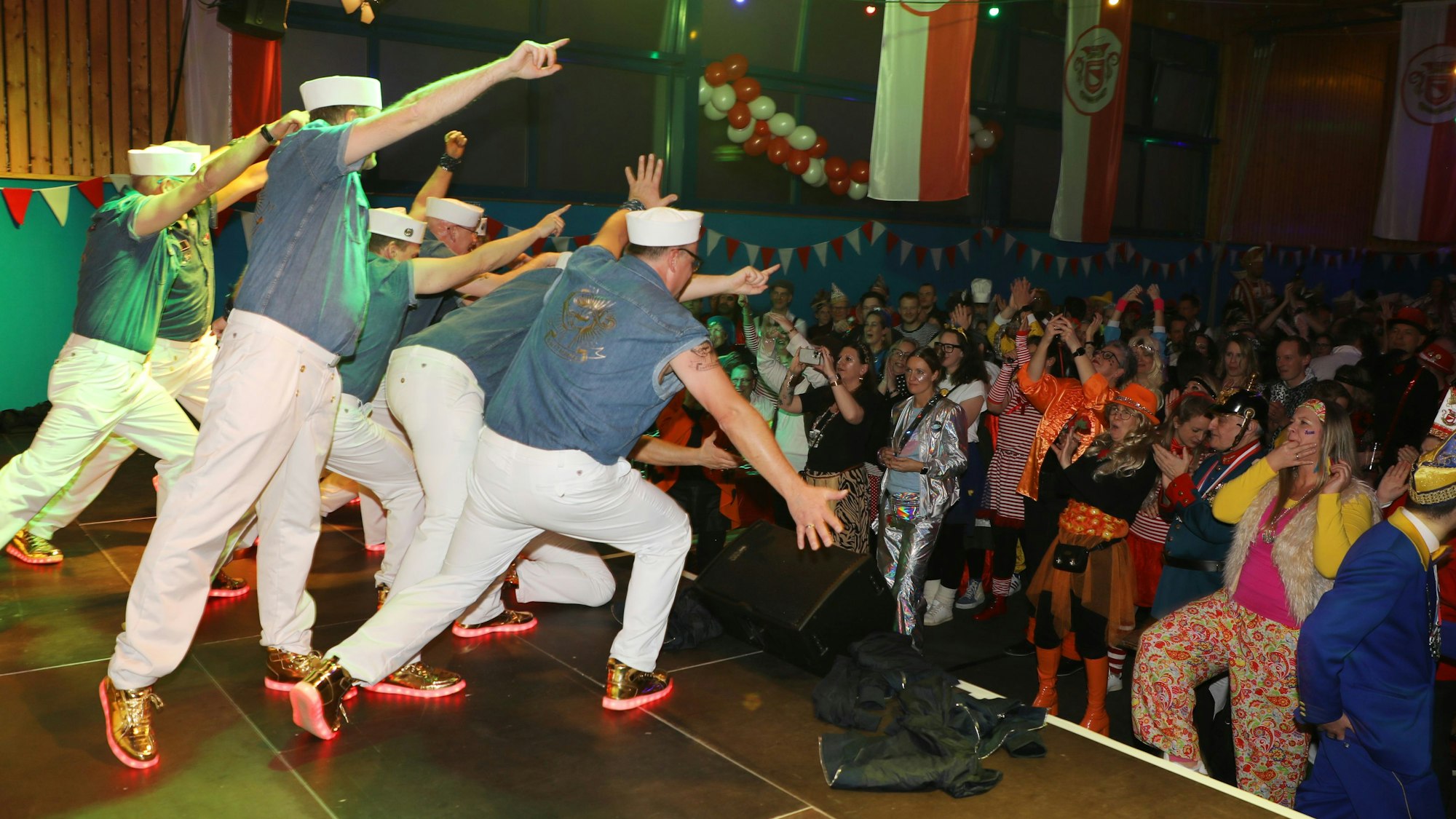 Männer in Matrosenuniformen tanzen vor Publikum.