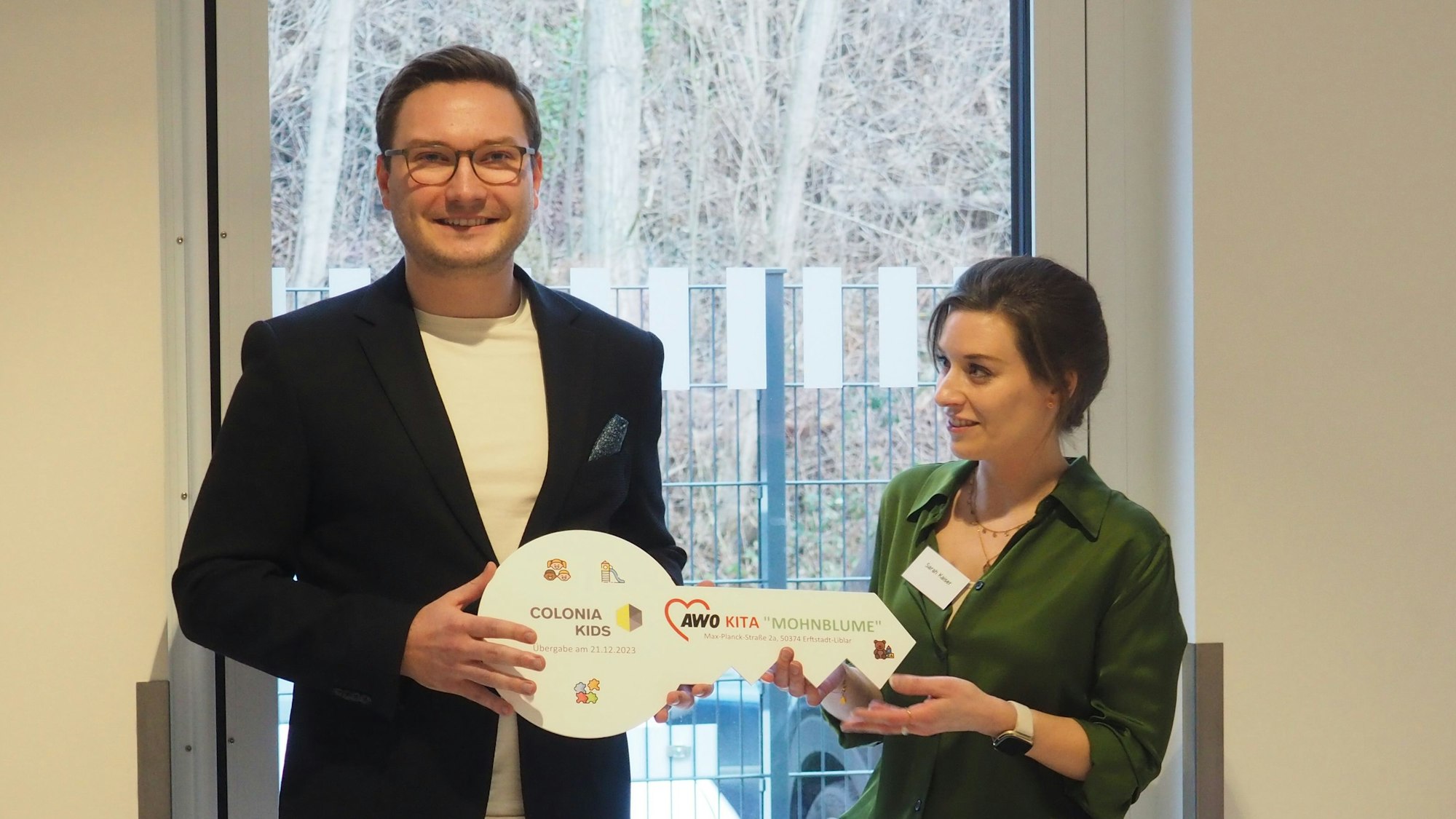 Ein Mann überreicht einer Frau einen großen Schlüssel aus Pappe.