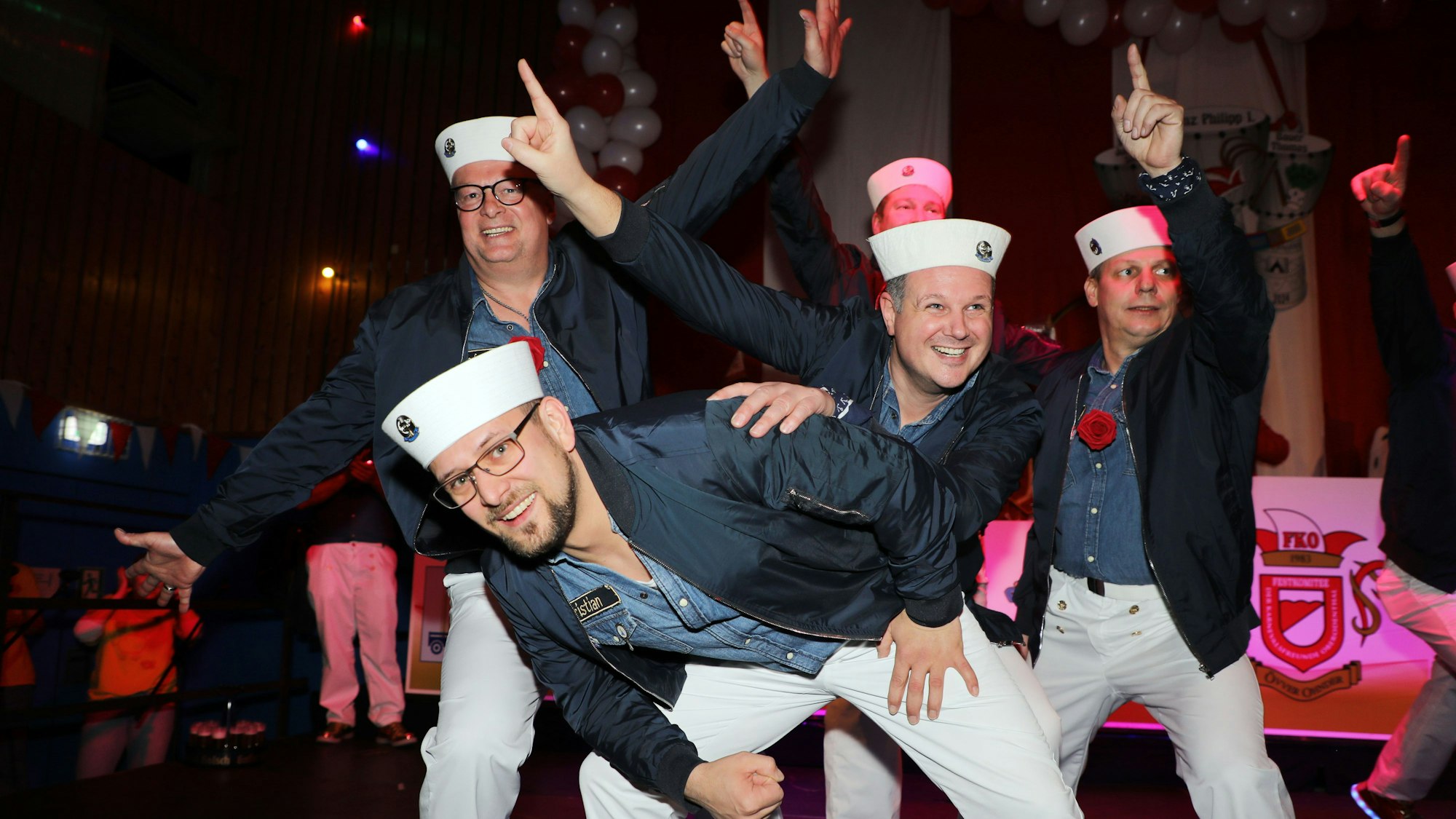 Männer in Matrosenuniformen tanzen vor Publikum.