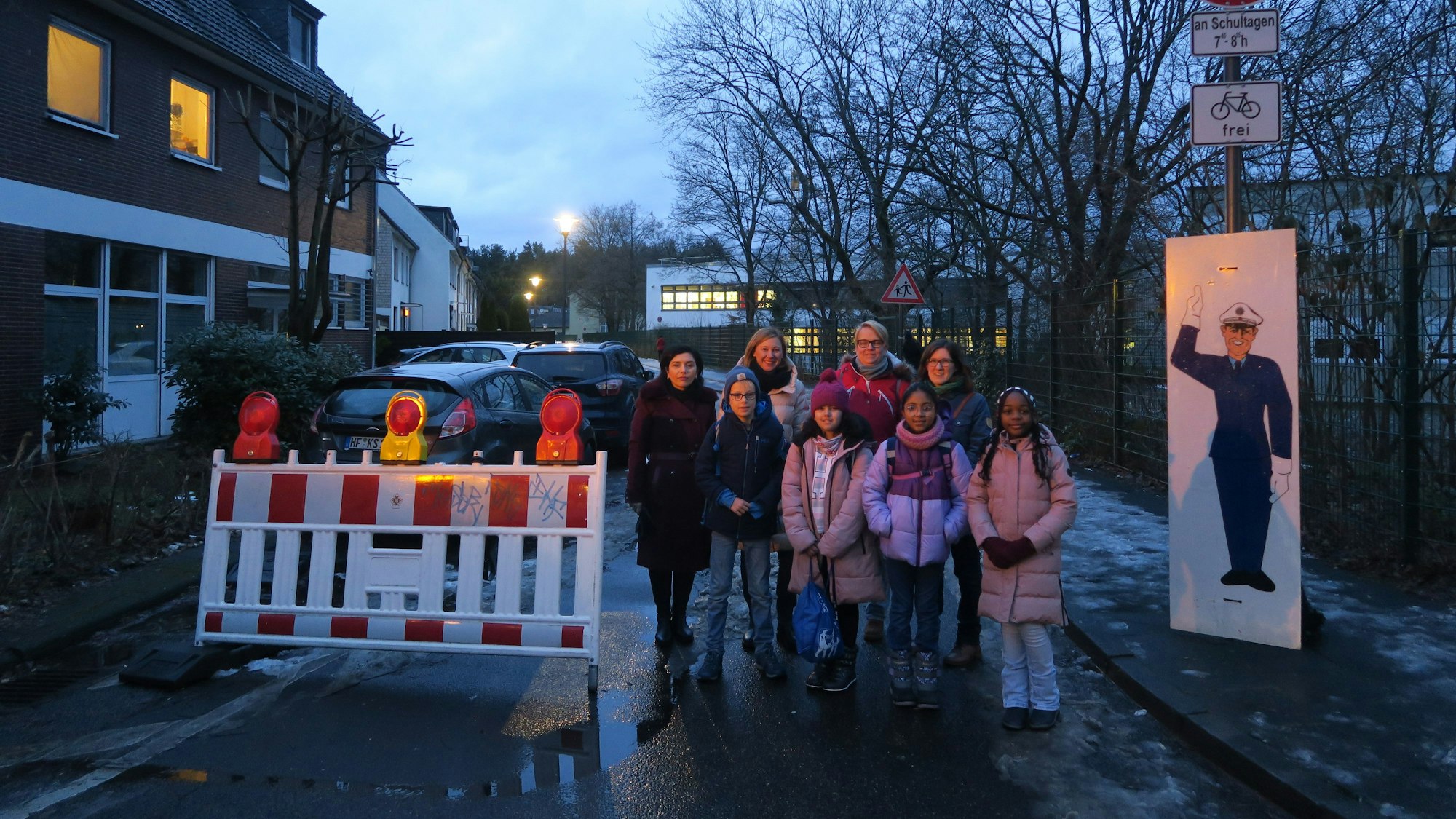 Kinder stehen an einer Straßenabsperrung.