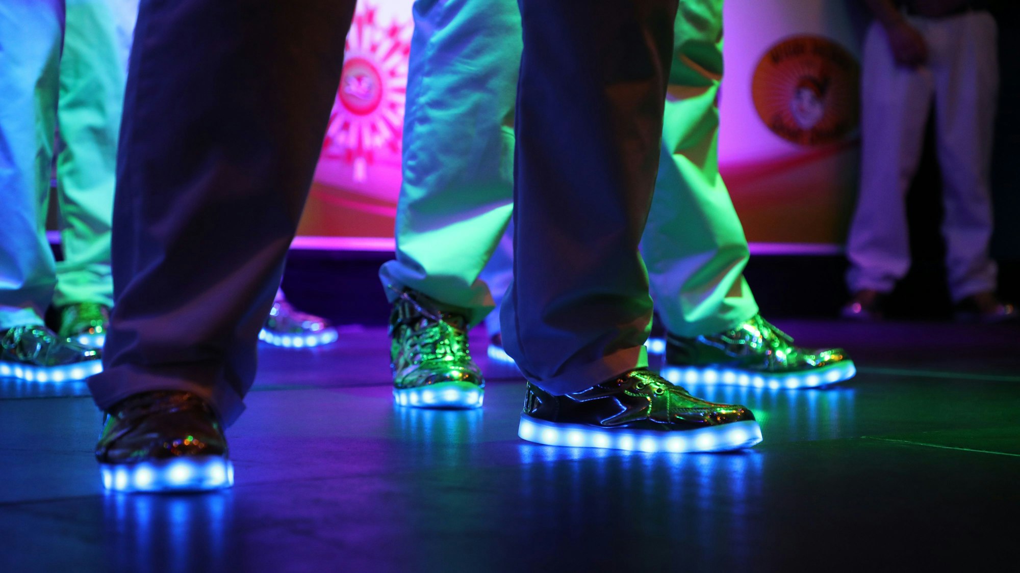 Leuchtende Schuhe sind auf einer dunklen Bühne zu sehen.