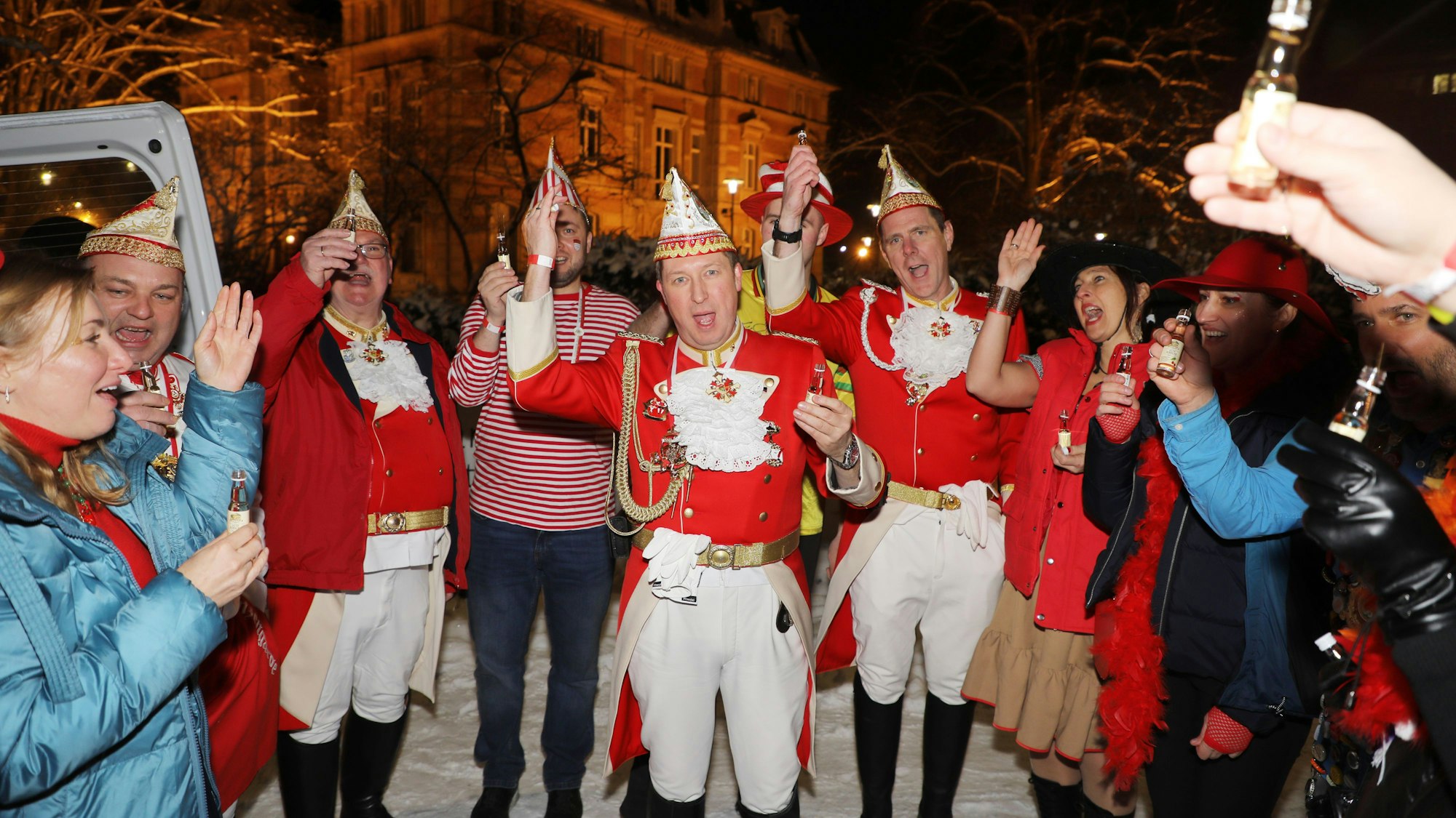Karnevalisten und Prinzengardisten stehen an einem Bus im Schnee, im Hintergrund ist die Villa Zanders zu sehen.