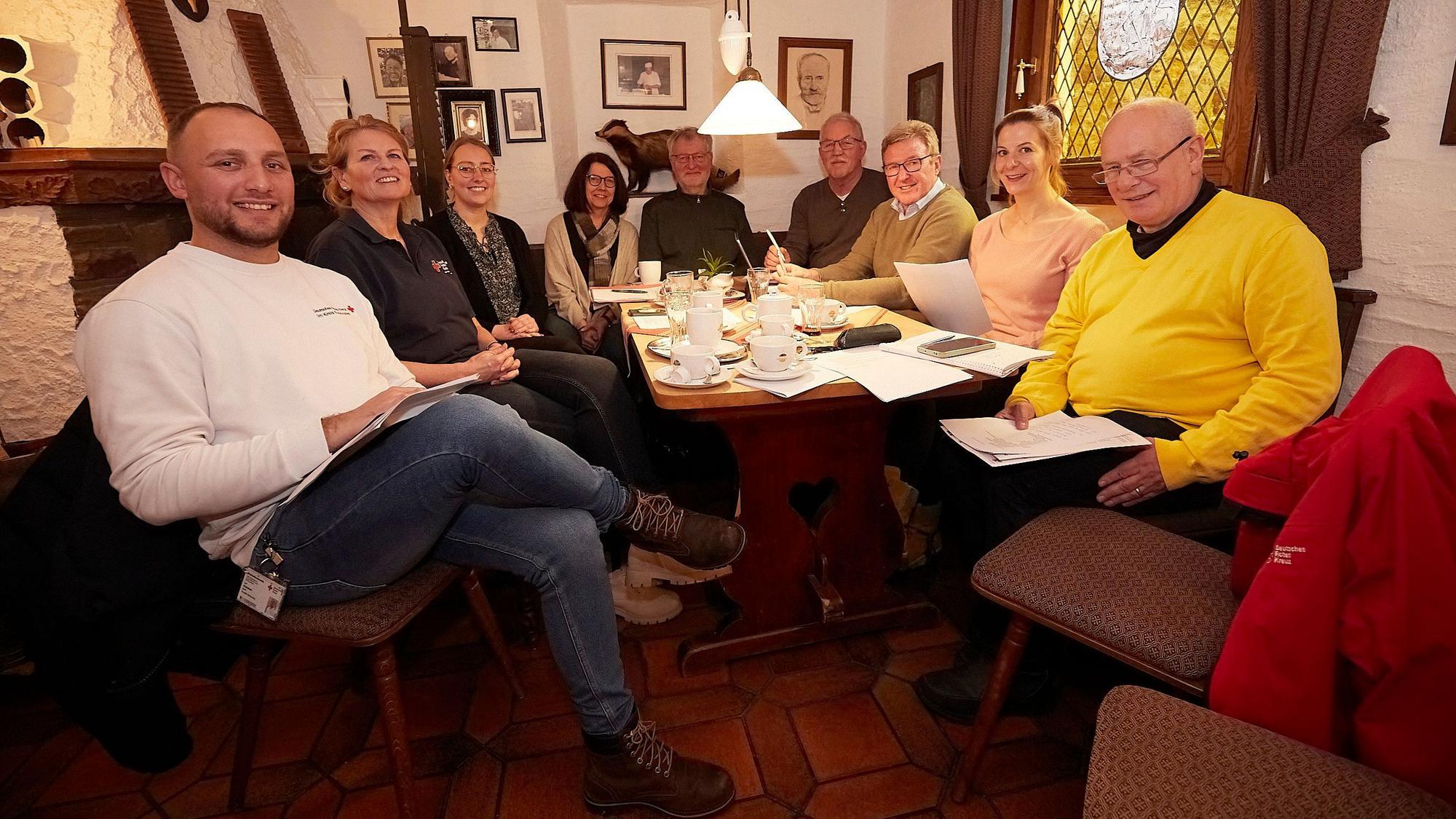 Einige Männer und Frauen sitzen in einem Café in Marmagen an einem Tisch.