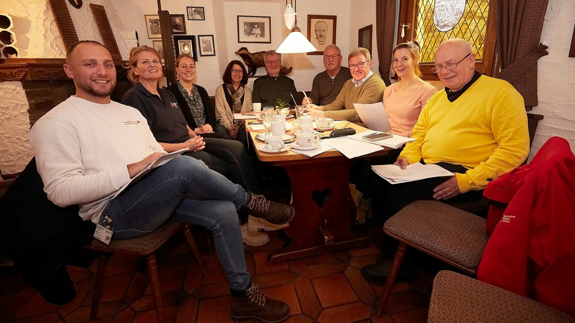 Einige Männer und Frauen sitzen in einem Café in Marmagen an einem Tisch.