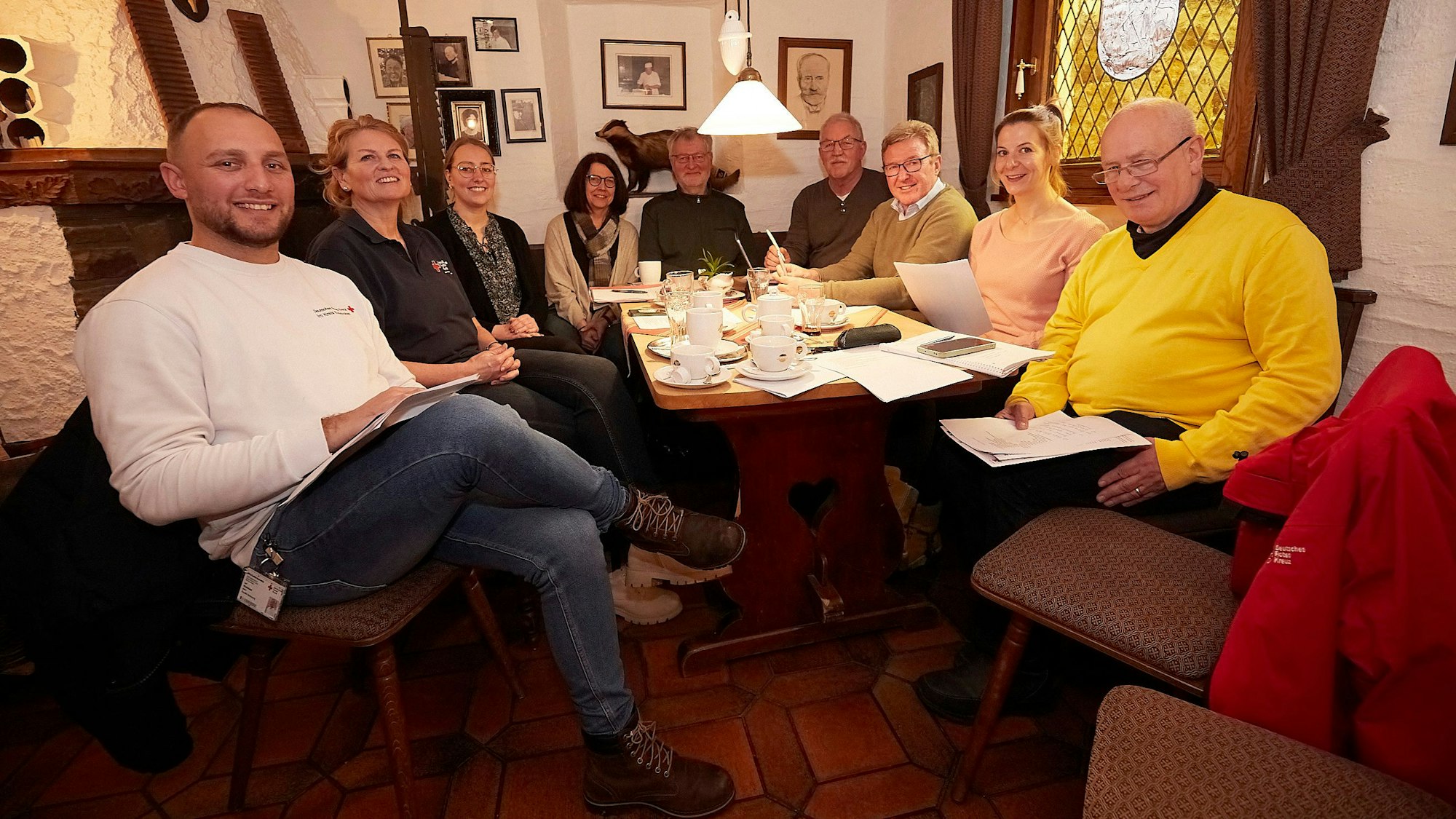 Einige Männer und Frauen sitzen in einem Café in Marmagen an einem Tisch.