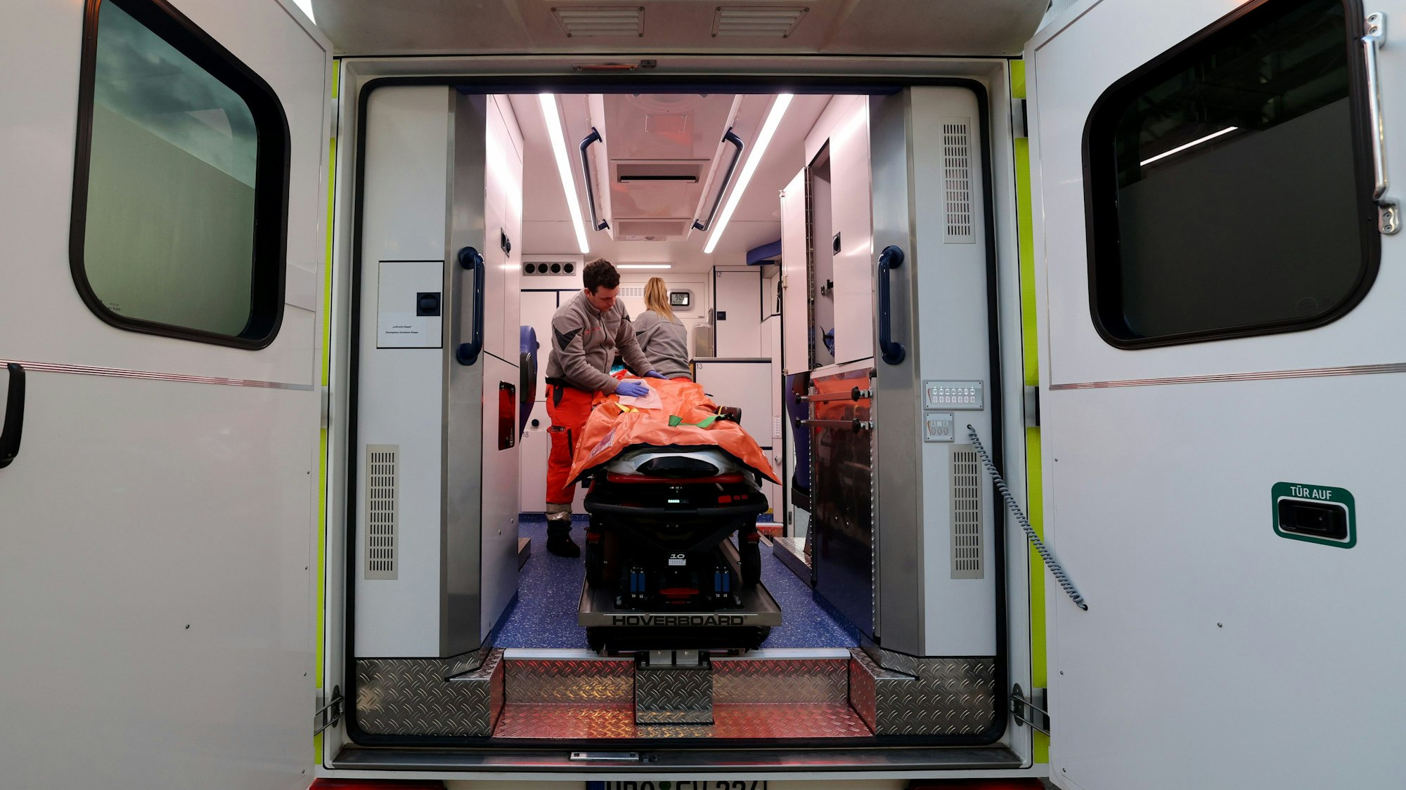 Blick in einen Rettungswagen, darin stehen zwei Notfallsanitäter.