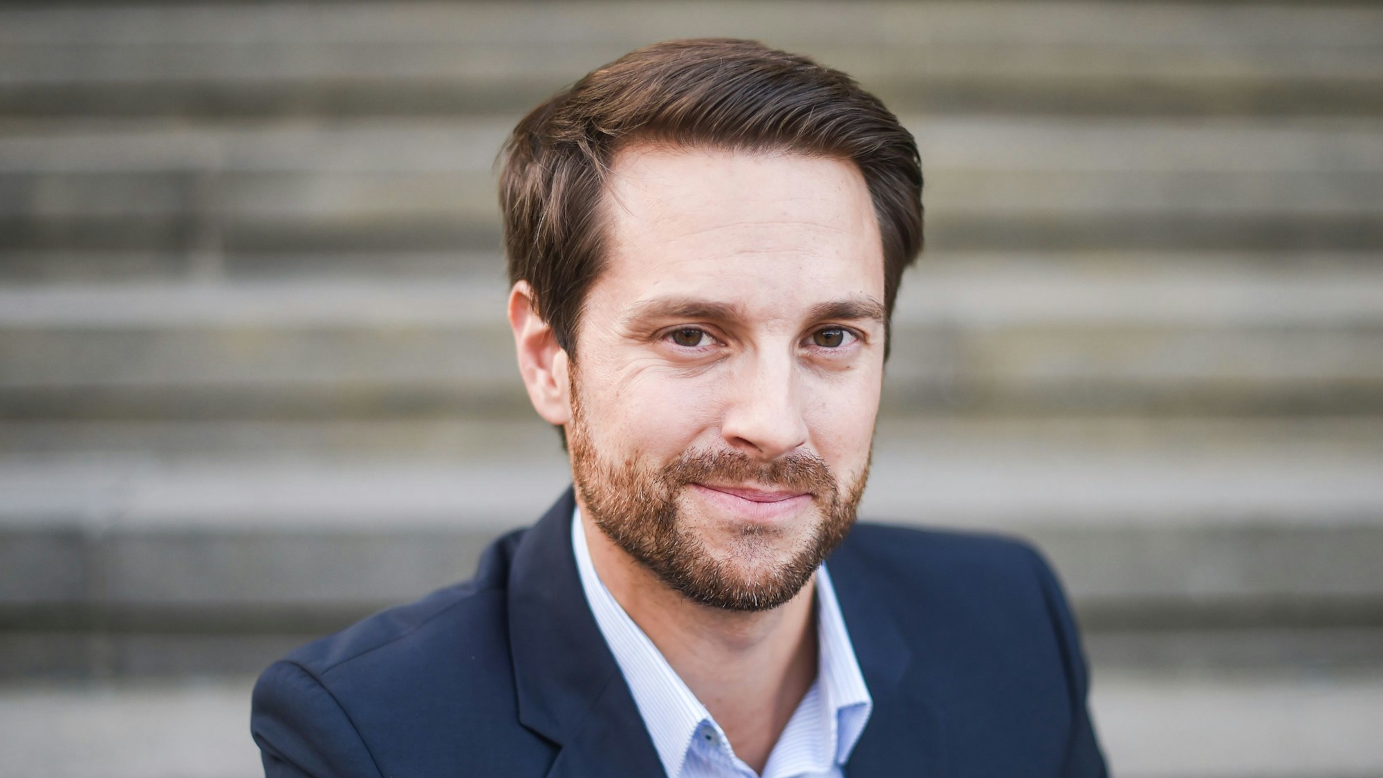 Mirko Drotschmann, Betreiber des Youtubekanals „MrWissen2go“, blickt in einem Anzug in die Kamera.