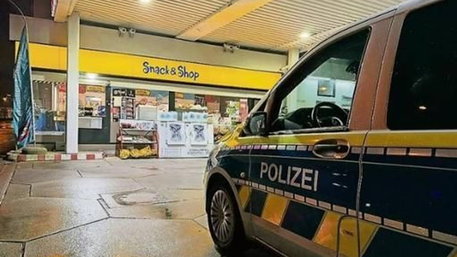Ein Polizeiauto steht an einer Tankstelle.
