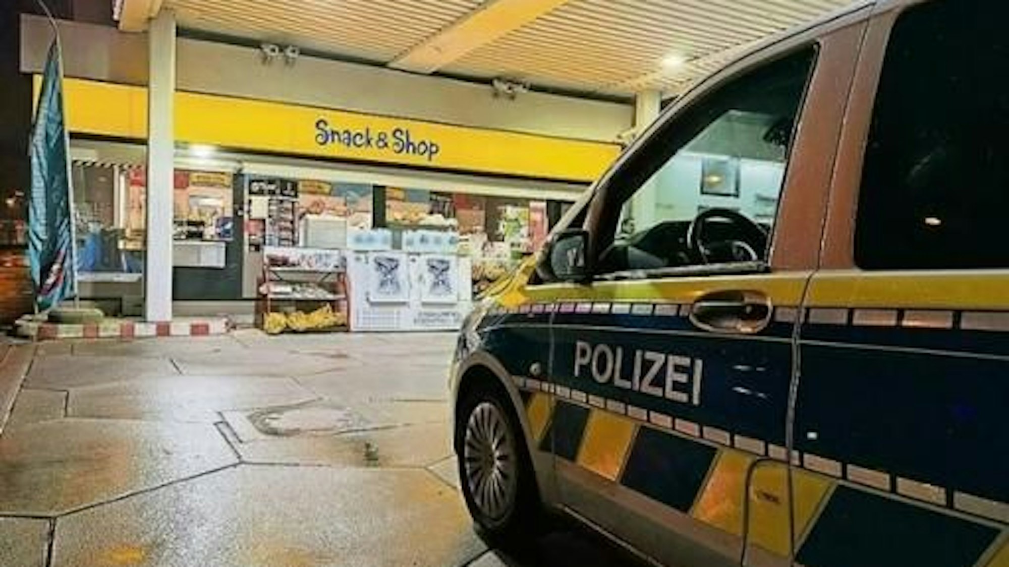 Ein Polizeiauto steht an einer Tankstelle.