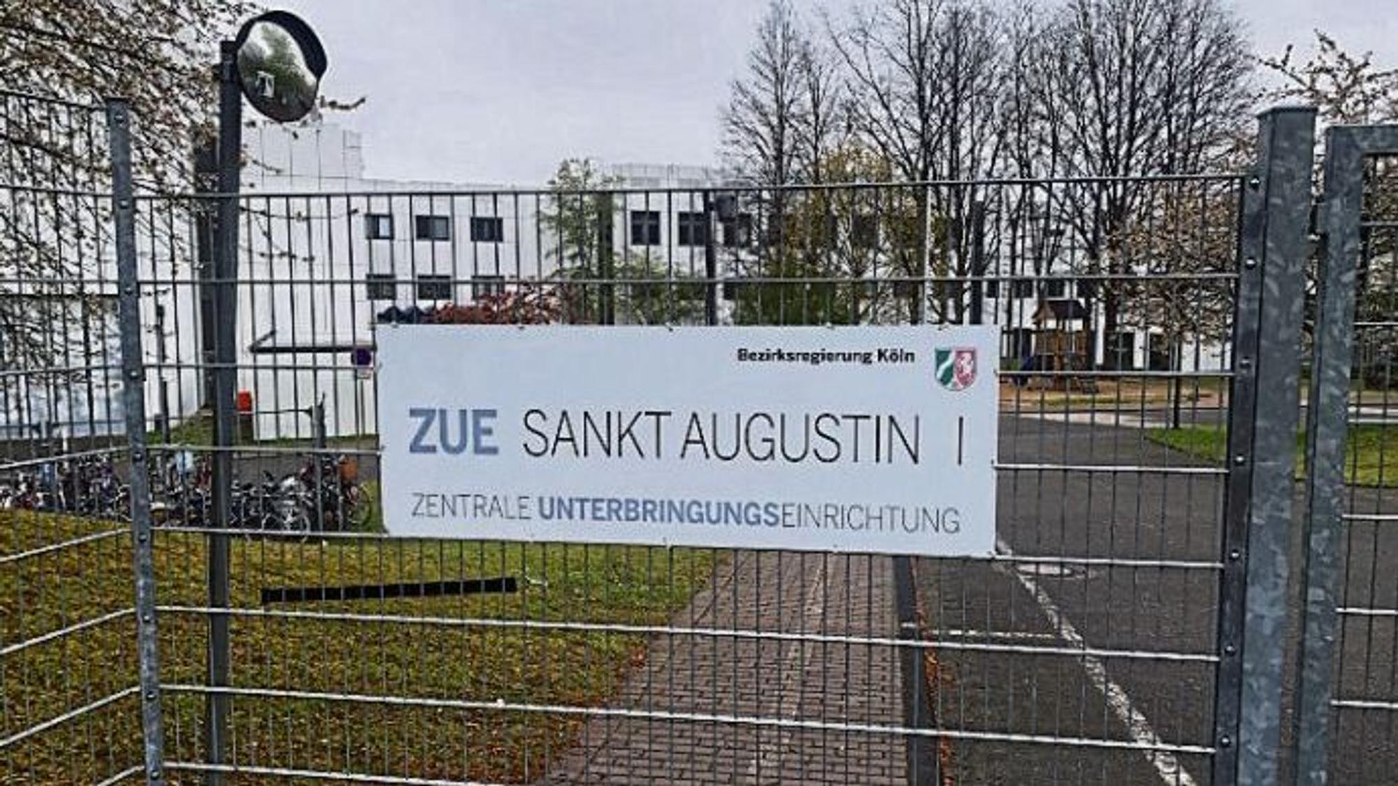 Ein Schild an einem Zaun weist auf die Zentrale Unterbringungseinrichtung für Geflüchtete (ZUE) in Sankt Augustin hin.