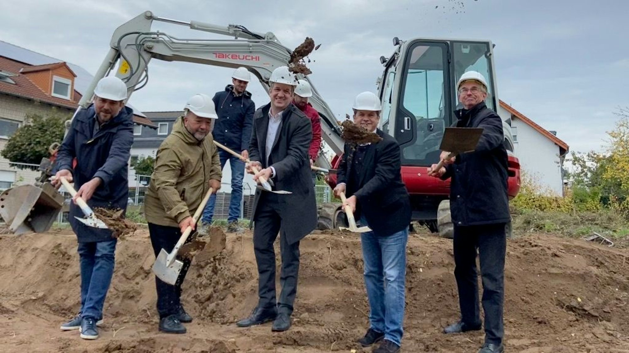 Sieben Männer mit Schaufeln beim ersten Spatenstich.