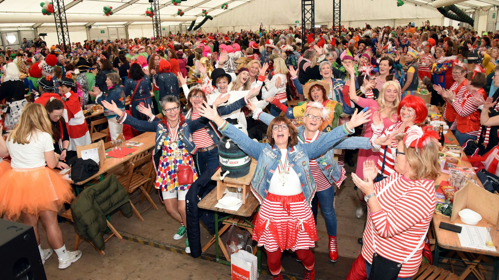 Ein volles Festzelt. Zahlreiche verkleidete Damen feiern Karneval.