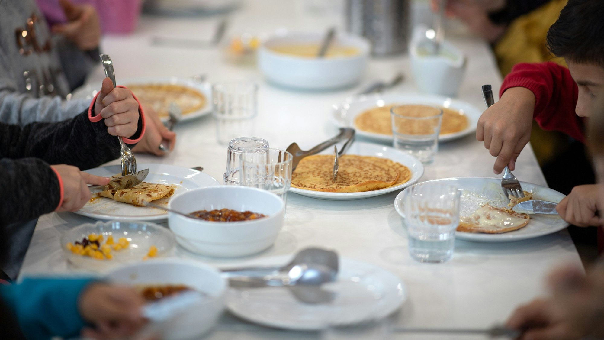 Kinder essen in der Kantine einer Grundschule Mittag.