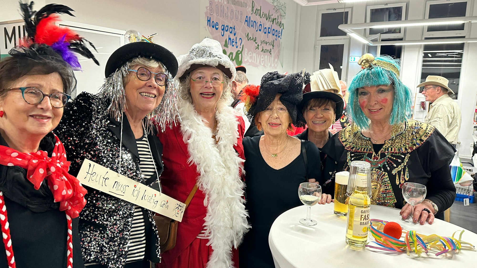 Sechs verkleidete Damen stehen an einem Stehtisch.