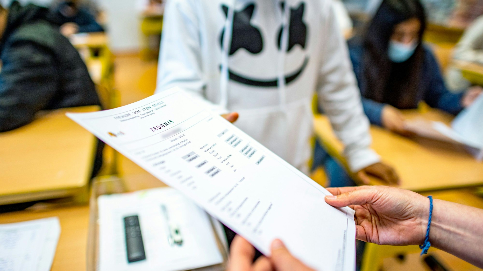 Ein Schüler nimmt das Zeugnis entgegen.