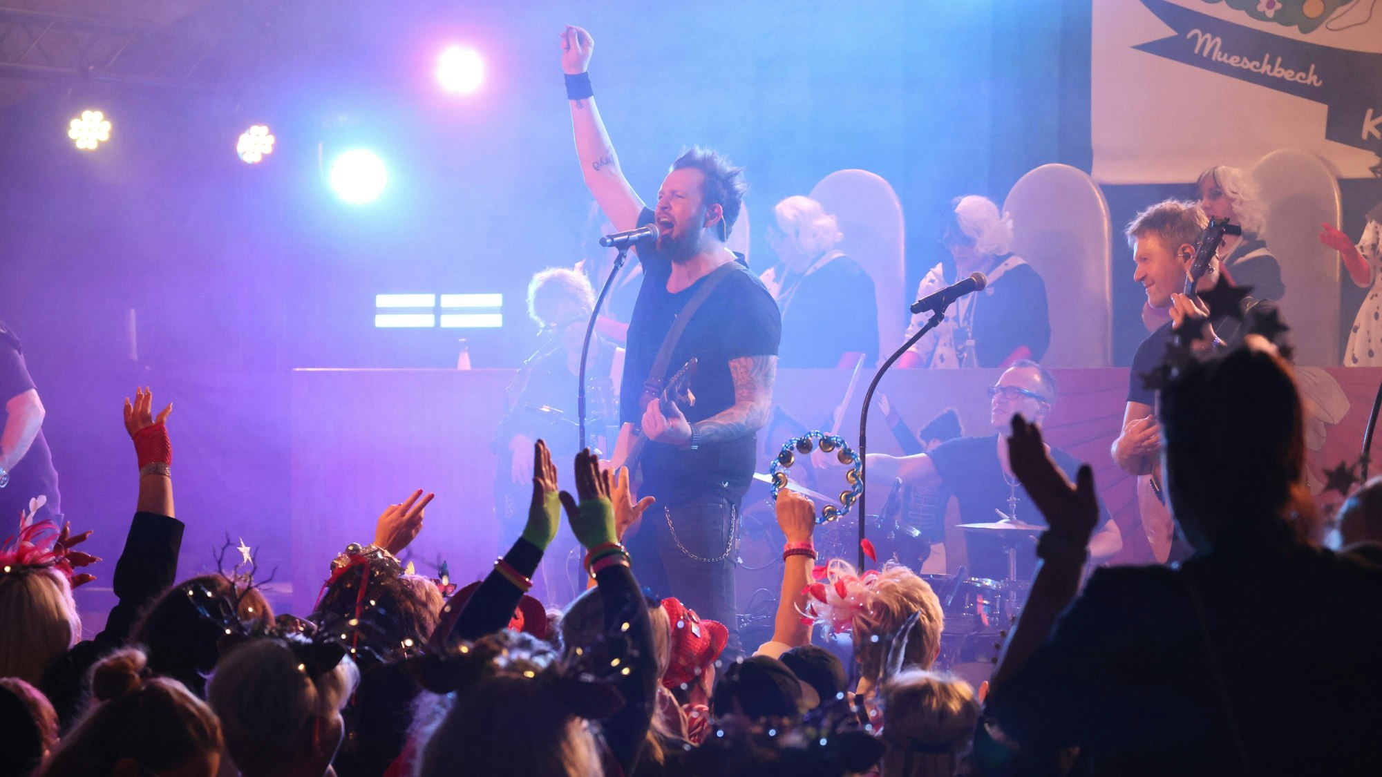 Die Band Paveier spielt auf einer Bühne in einem Karnevalsfestzelt.