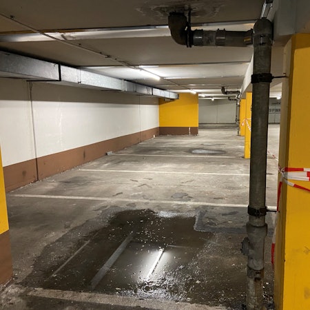 Auf dem Bild ist eine Pfütze in der Tiefgarage zu sehen.