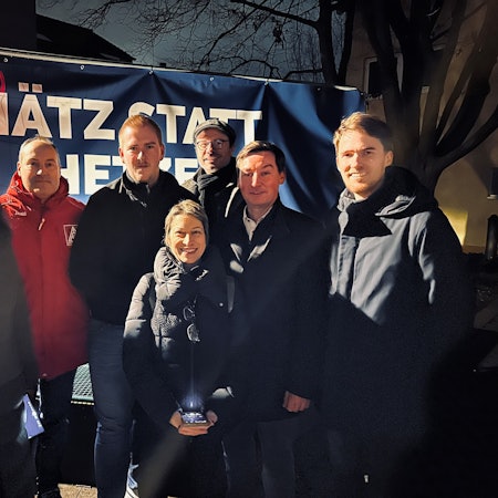 Männer und Frauen stehen vor einem Banner mit der Aufschrift „Hätz statt Hetze“.
