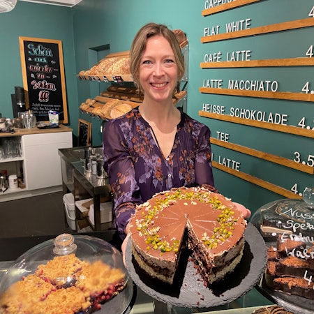 Auf dem Bild ist die Inhaberin des neuen Cafes mit einem Kuchen zu sehen