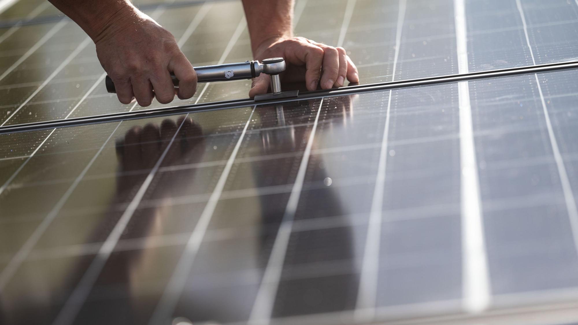 Ein Arbeiter montiert Photovoltaikmodule auf einem Dach.
