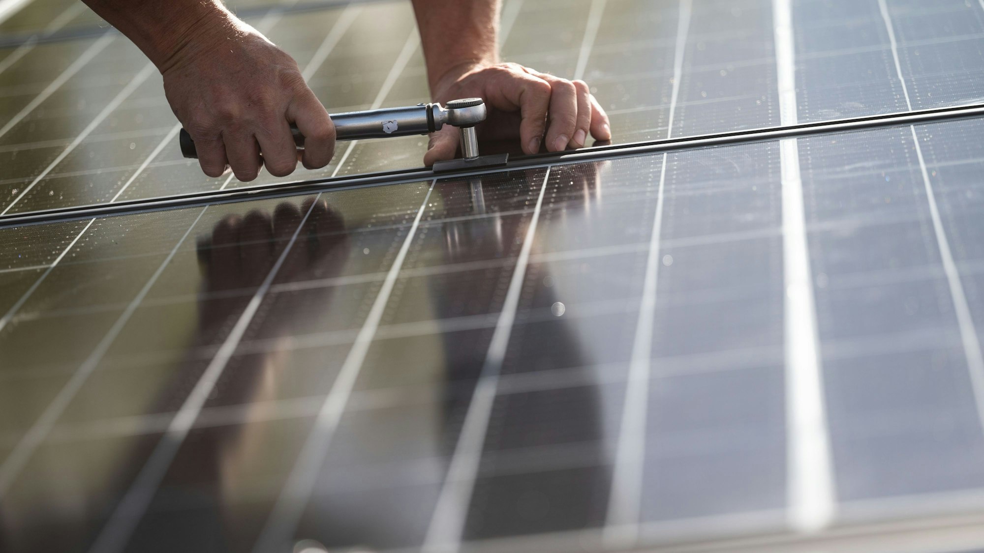 Ein Arbeiter montiert Photovoltaikmodule auf einem Dach.