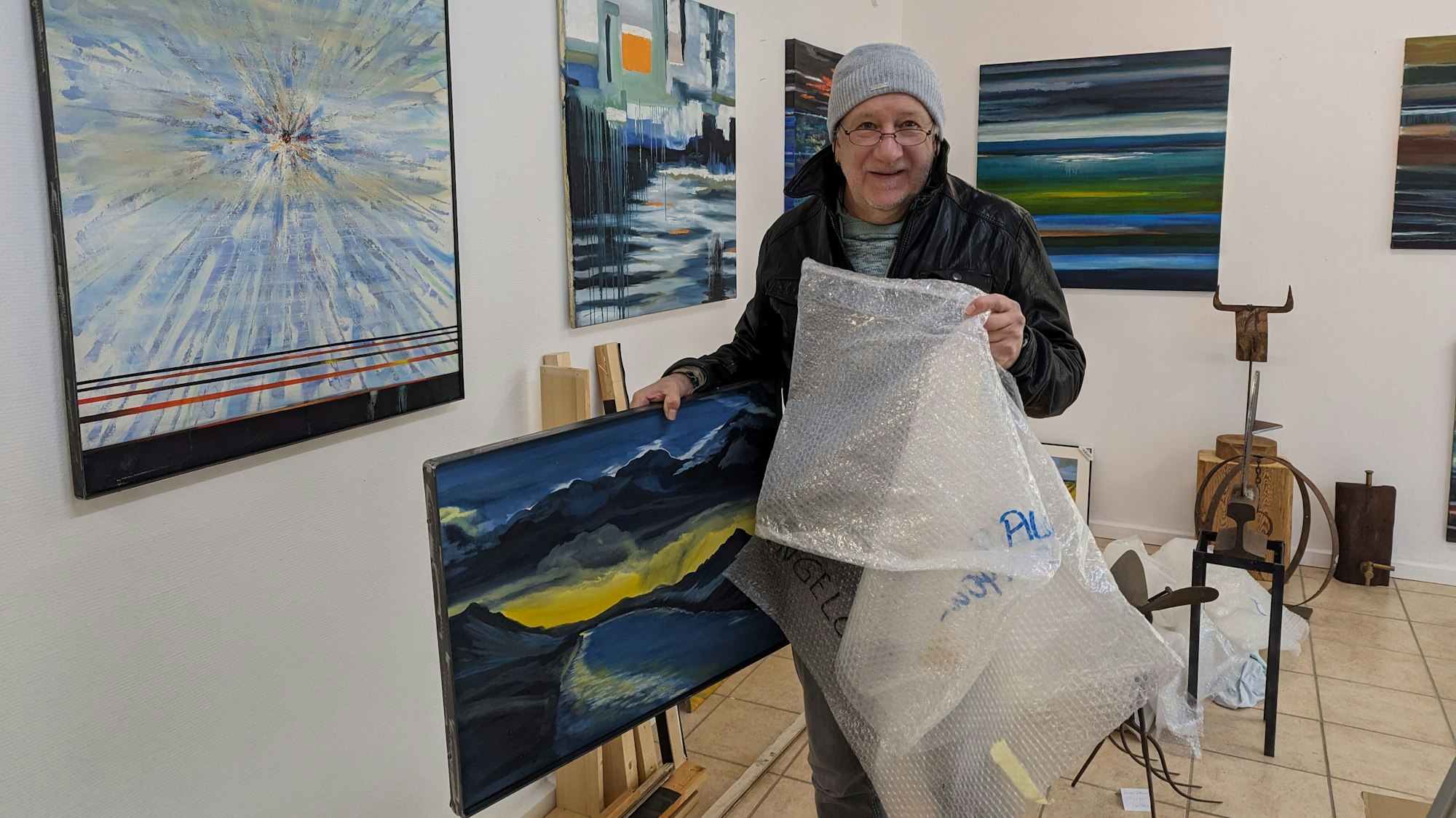 Ein Künstler verpackt in seiner Galerie ein Ölbild in Luftpolsterfolie.