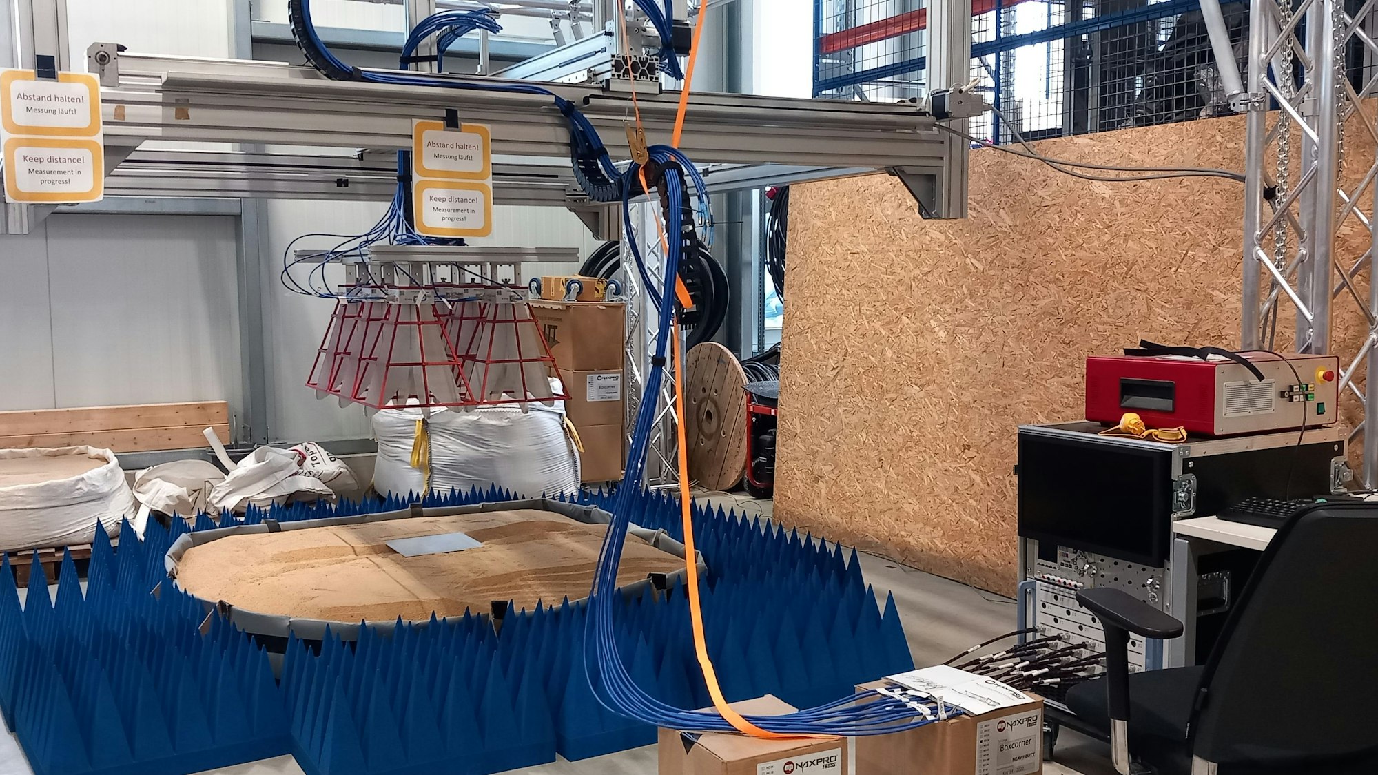 Zwölf Vivaldi-Antennen sind auf ein Sandbecken gerichtet. Blaue Kegel schlucken Radarstrahlen am Rand des Testbereichs.