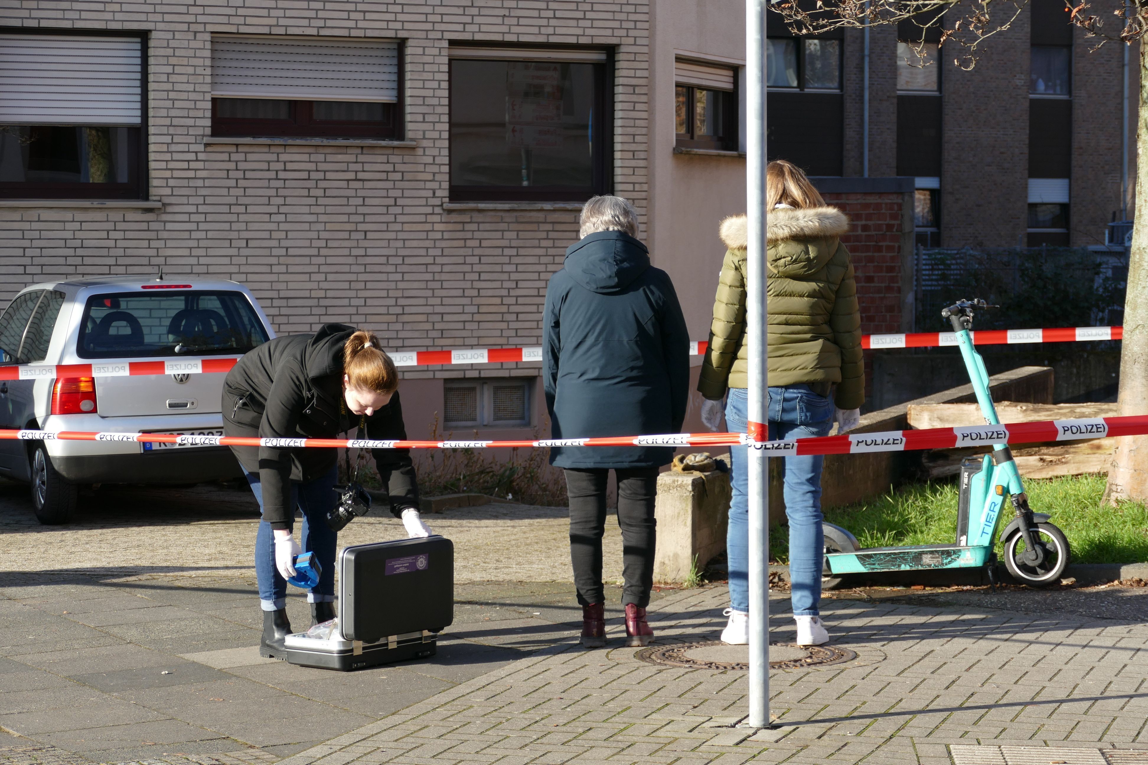 Drei Frauen stehen in einem durch Flatterband abgesperrten Bereich.