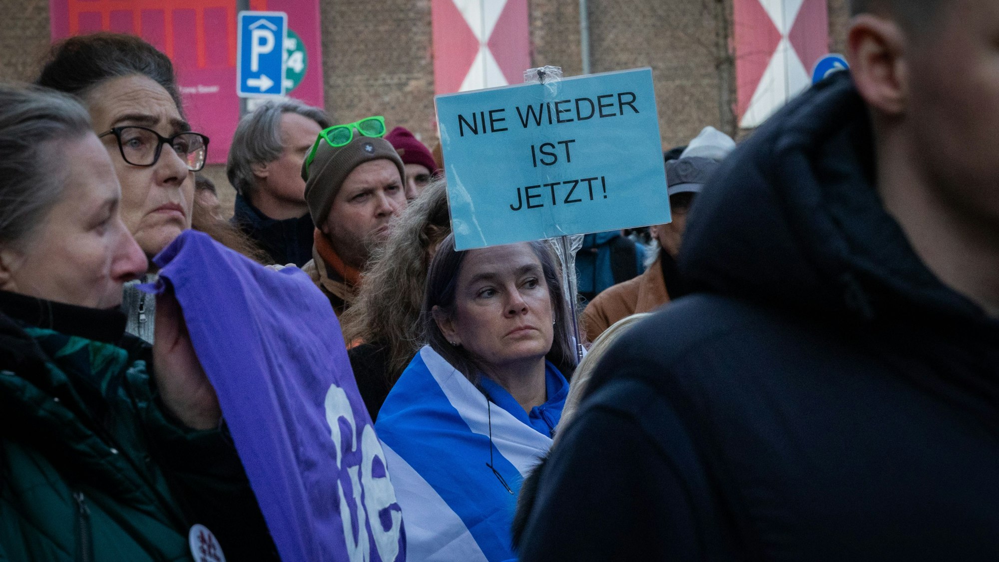 Eine Frau trägt ein Schild mit der Aufschrift „Nie wieder ist jetzt“.