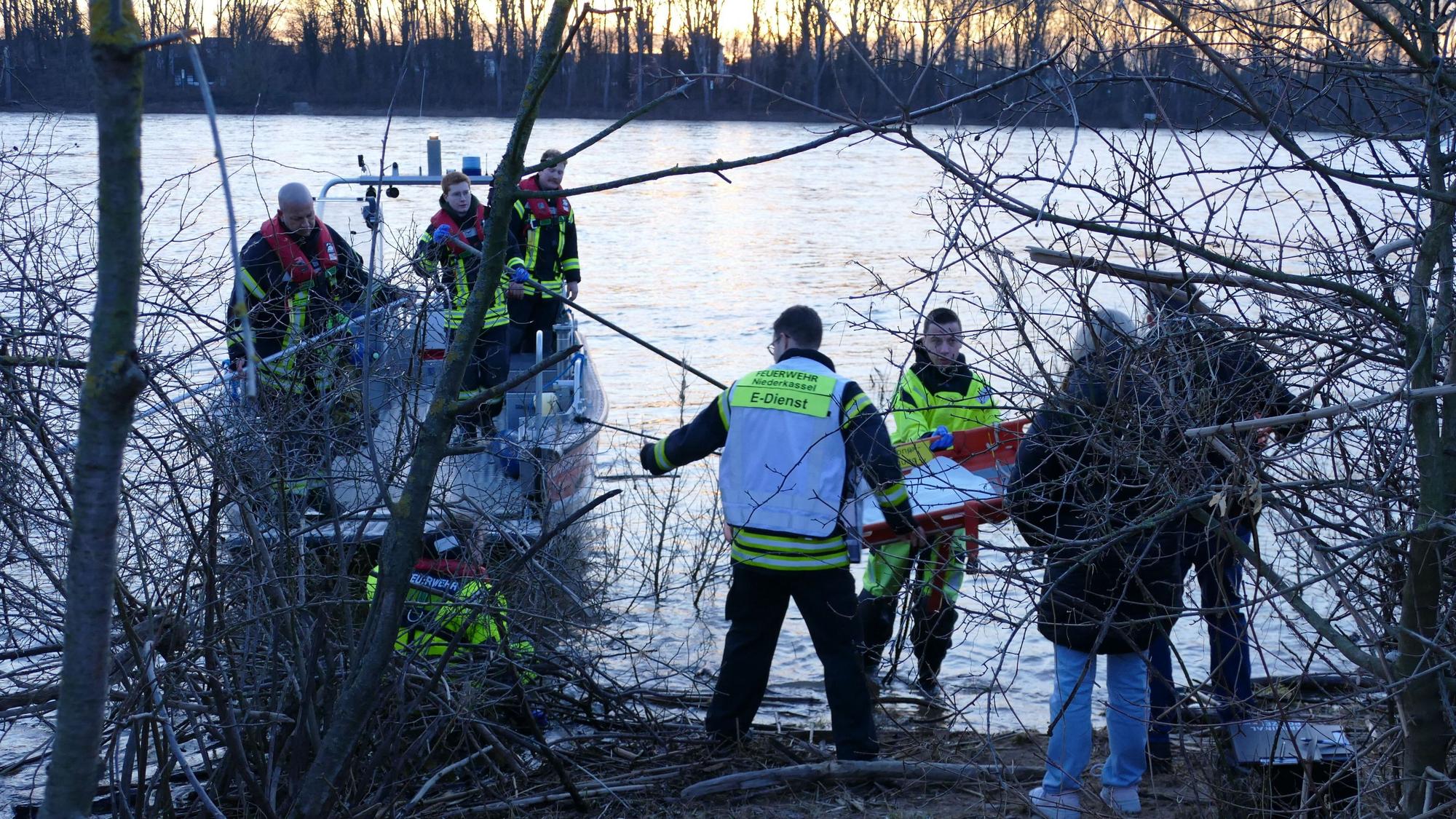 Feuerwehrleute und Angehörige der Kriminalpolizei stehen im Ufergestrüpp.