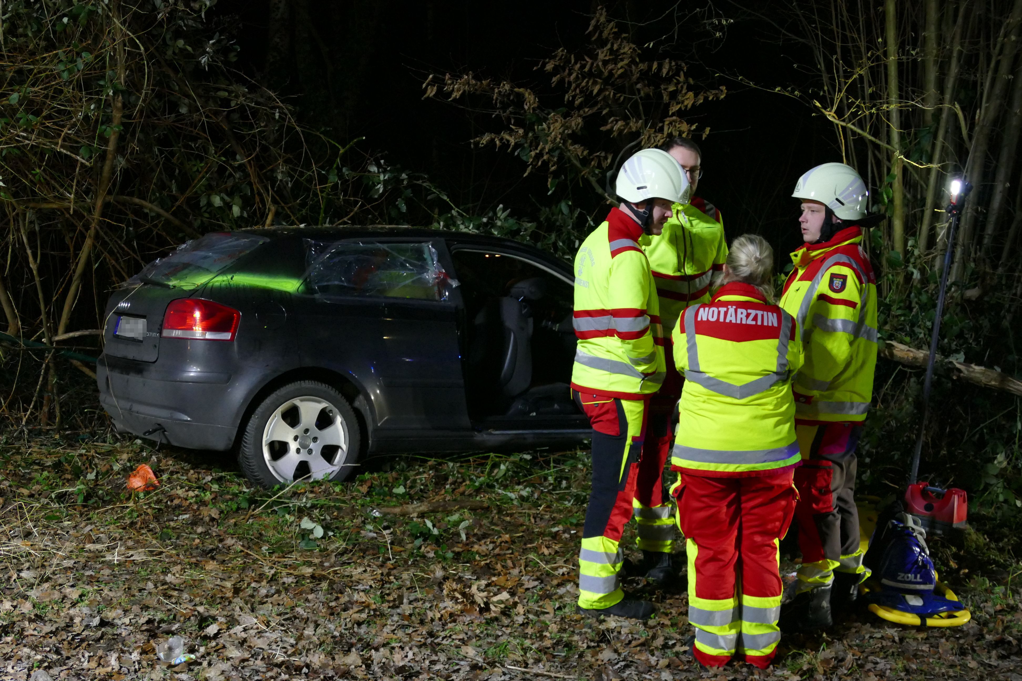 Rettungskräfte stehen um das verunglückte Auto herum.