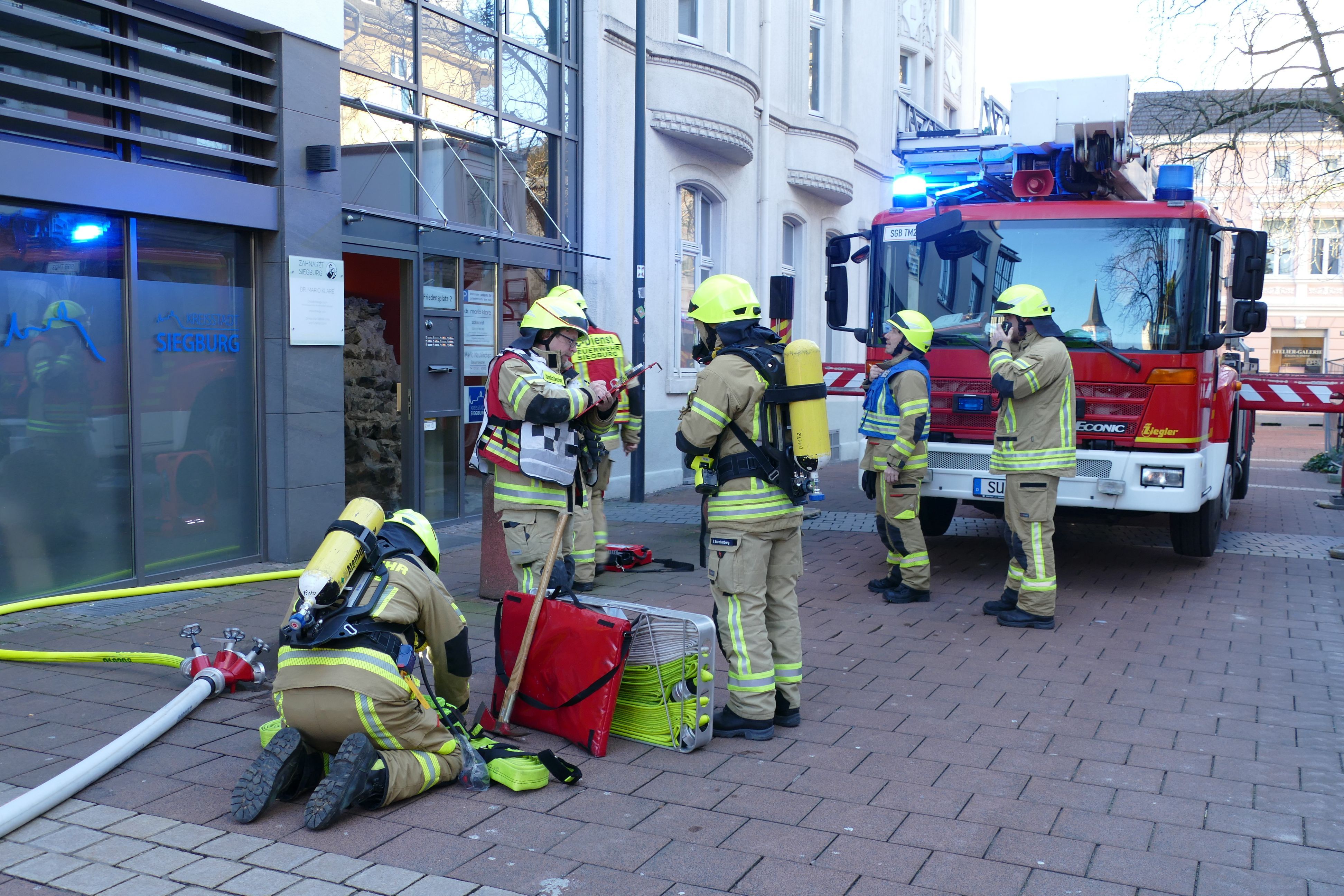 Feuerwehrleute vor dem Eingang des Gebäudes am Friedensplatz.