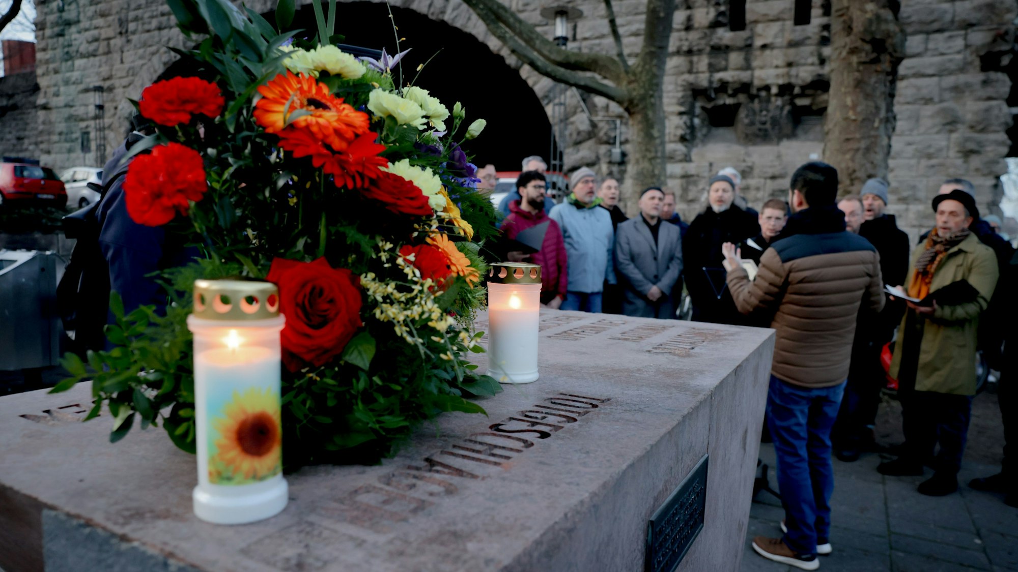 Auf einem Mahnmal liegen Blumen und Kerzen.
