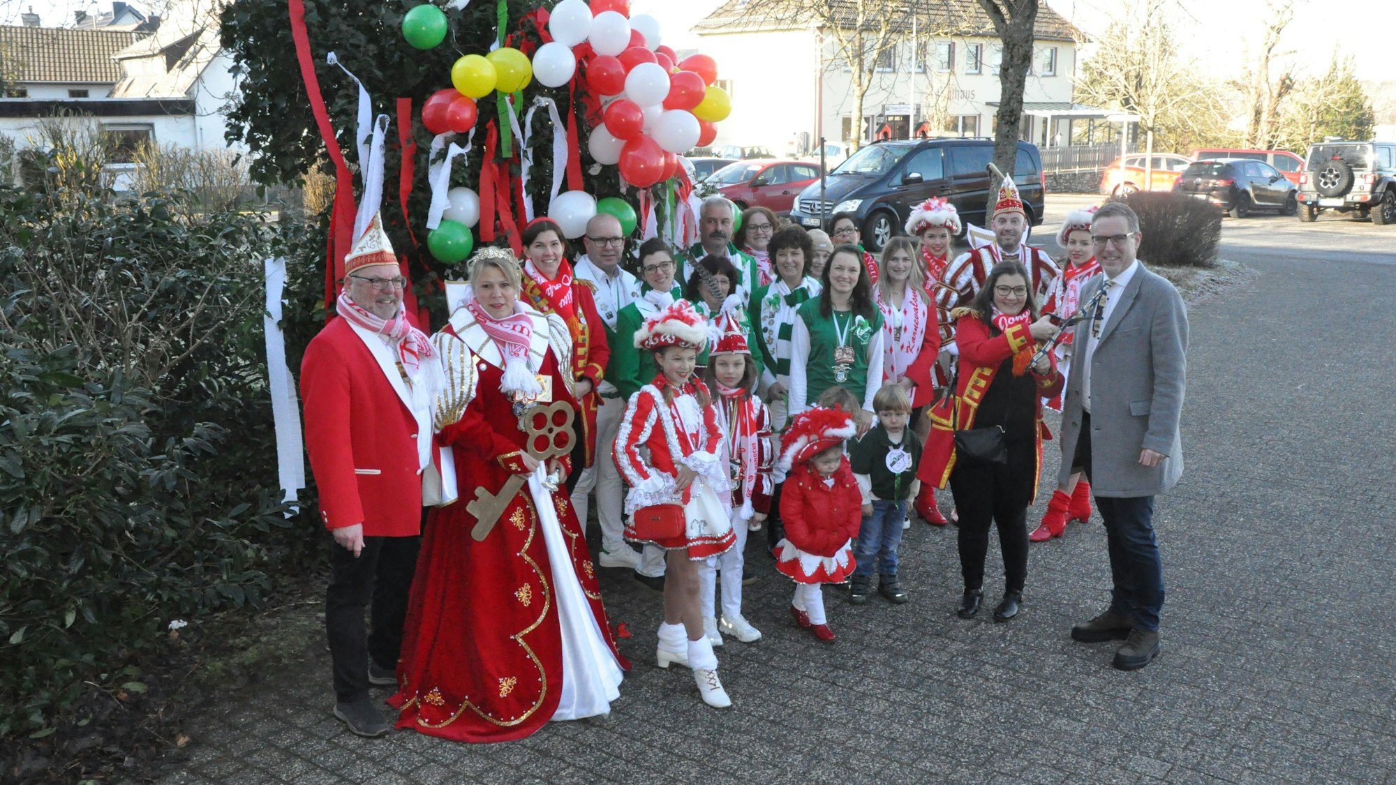Vertreter und Vertreterinnen der Karnevalsgesellschaften und -vereine der Gemeinde Nettersheim stehen vor einem mit Luftballons und Krepppapier geschmücktem Busch am Rathaus in Zingsheim.