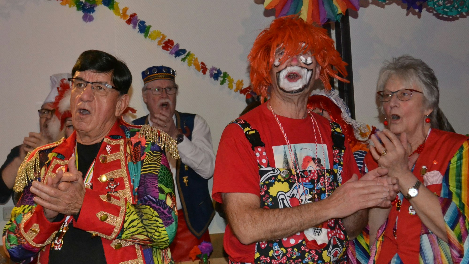 Bunt kostümierte Männer und Frauen klatschen und singen.