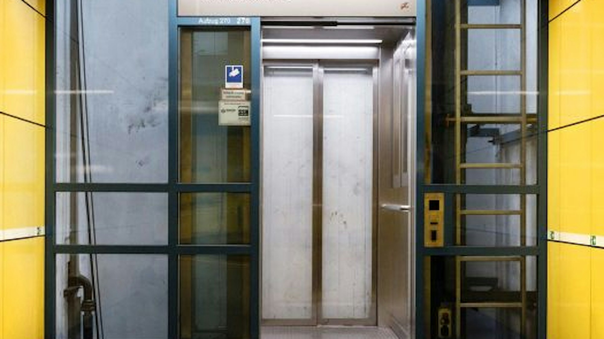 Ein gläserner Aufzug, die Türen sind geöffnet.