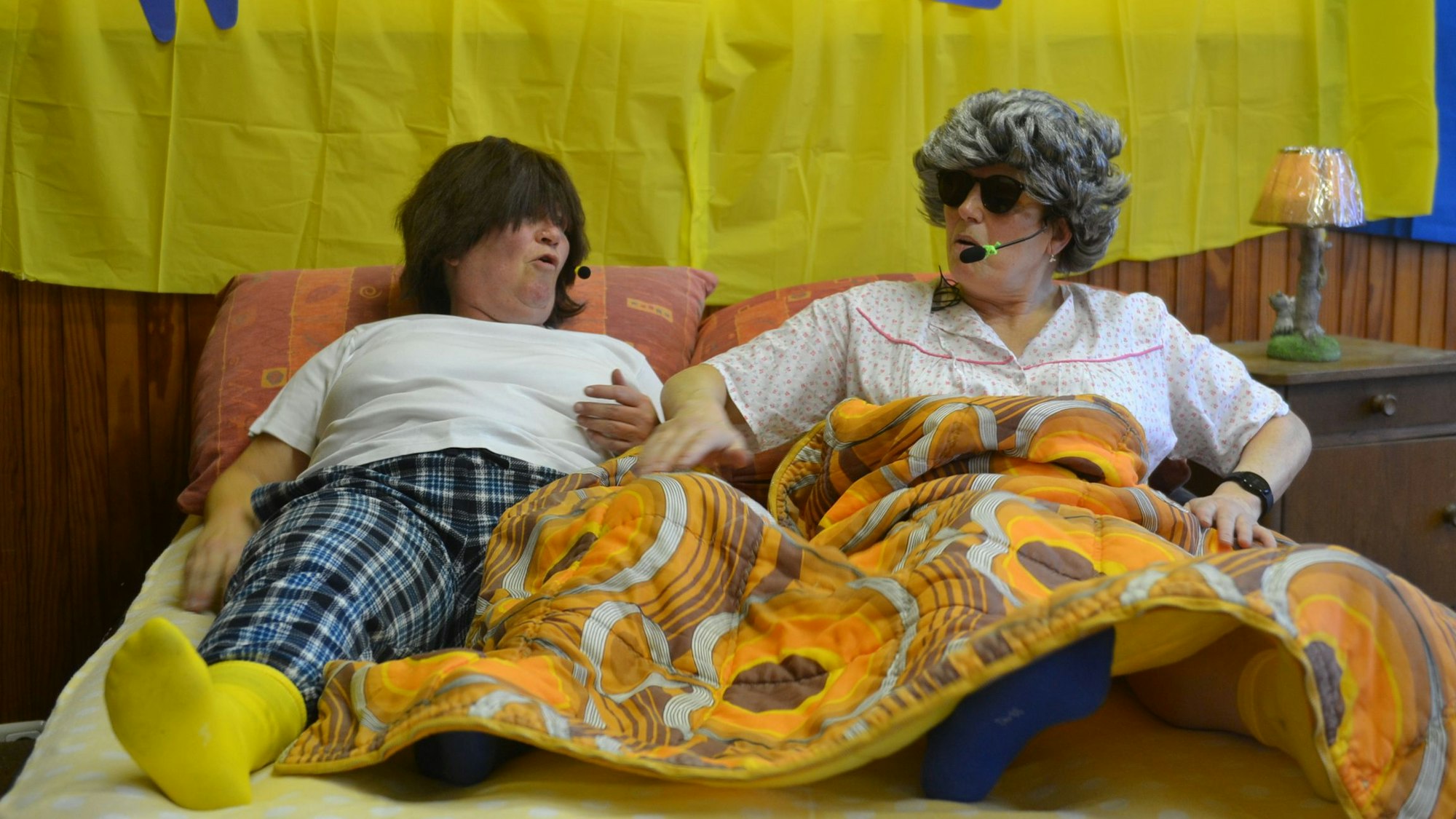 Claudia Schäfer und Gerdis Reuter liegen verkleidet in einem Bett.