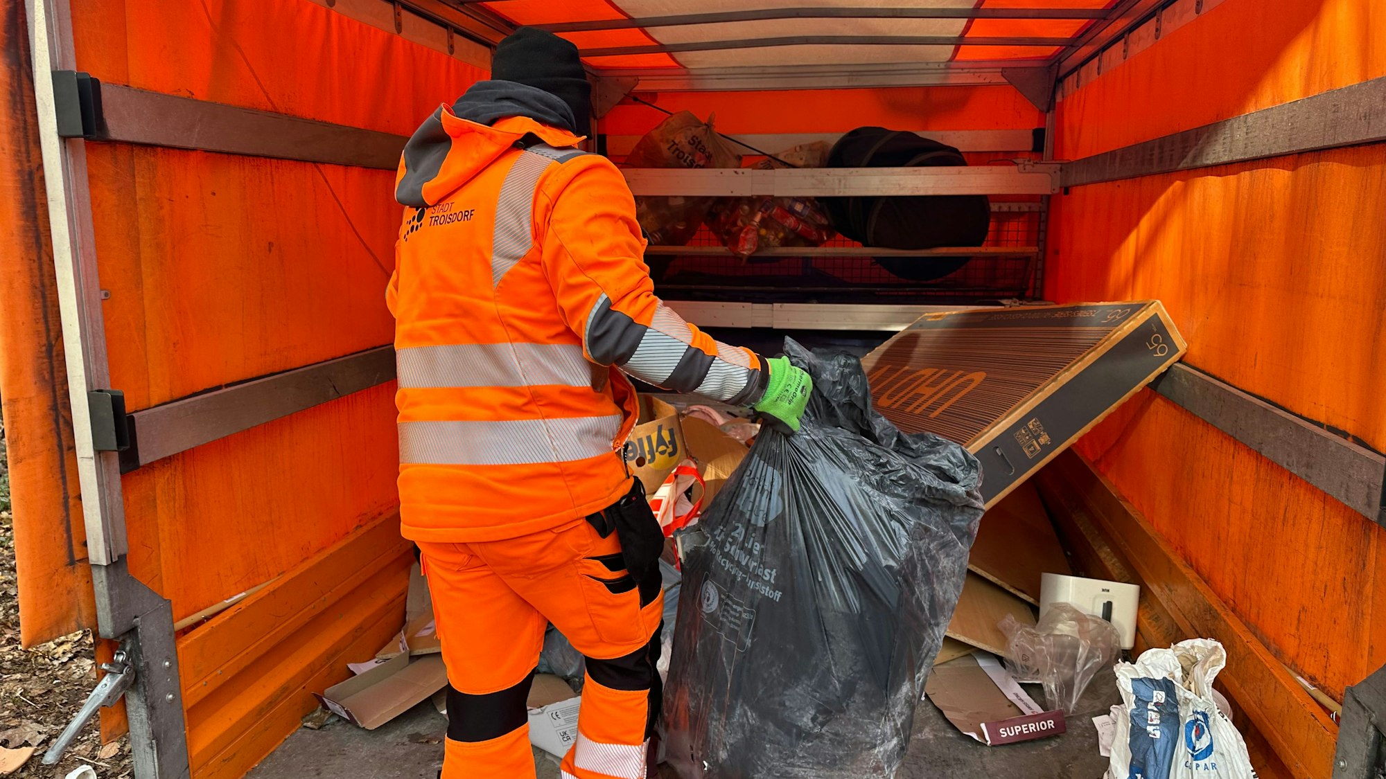 Rechts ein Sack mit Bauschutt, hinten der Karton eines Flachbildfernsehers. Alles wird zum Abtransport verladen.