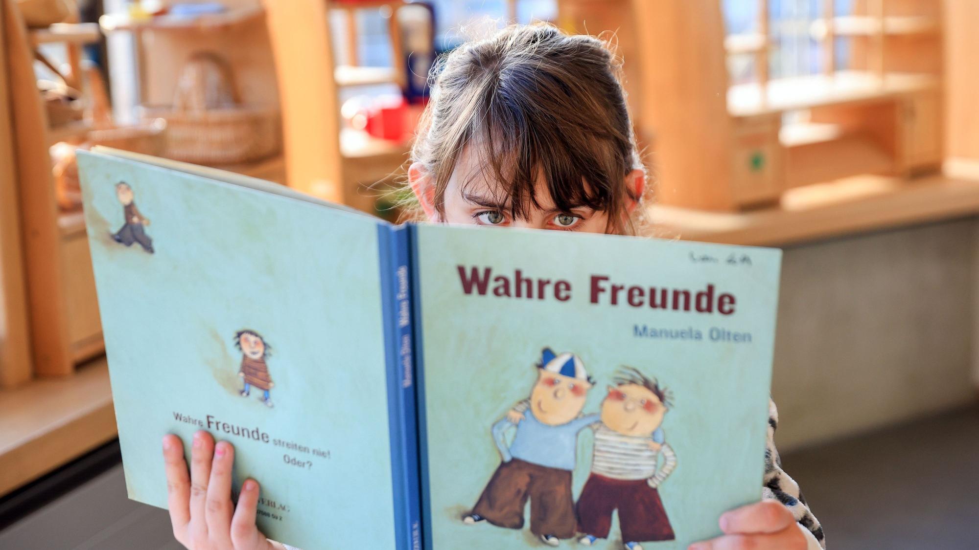 Evanthia liest in einem Bilderbuch.
