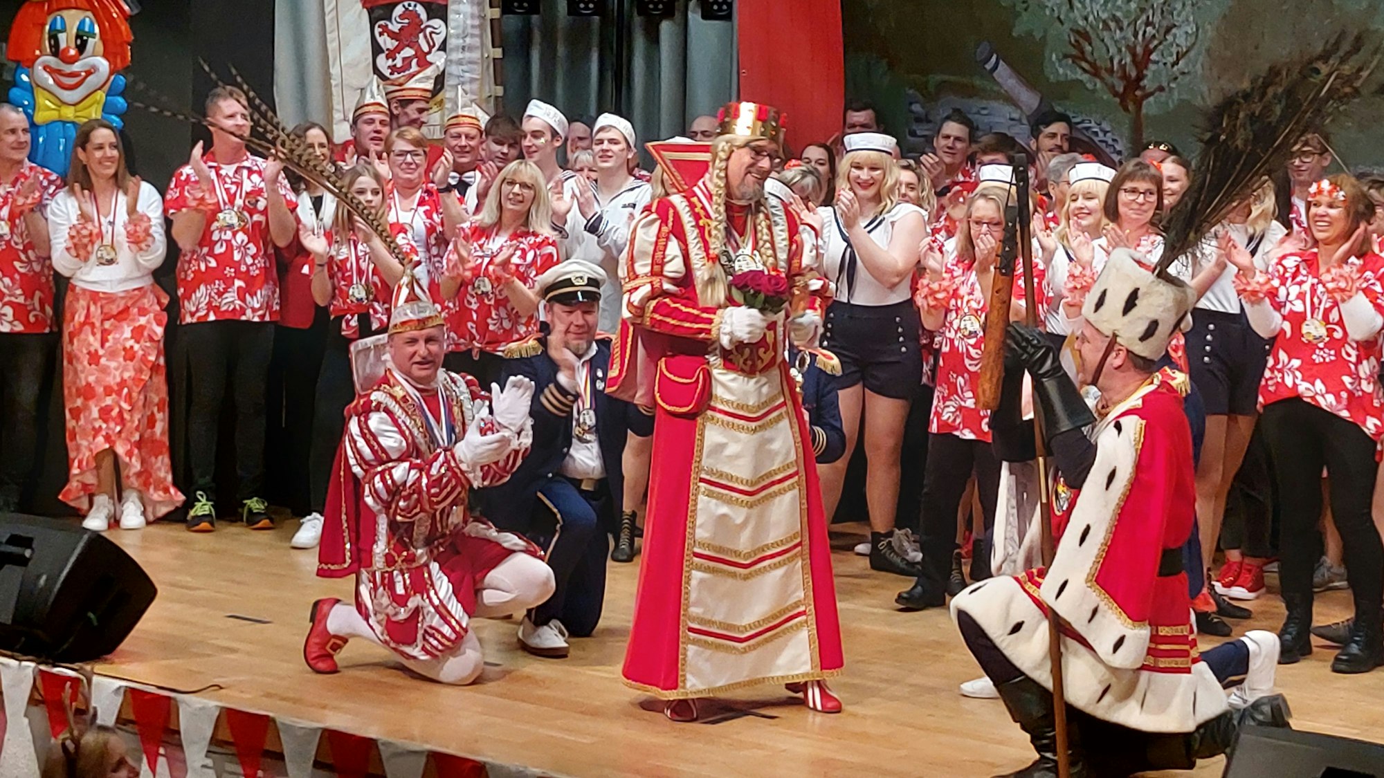 Prinz und Bauer gehen auf der Bühne vor der Karnevalsjungfrau in ddie Knie.