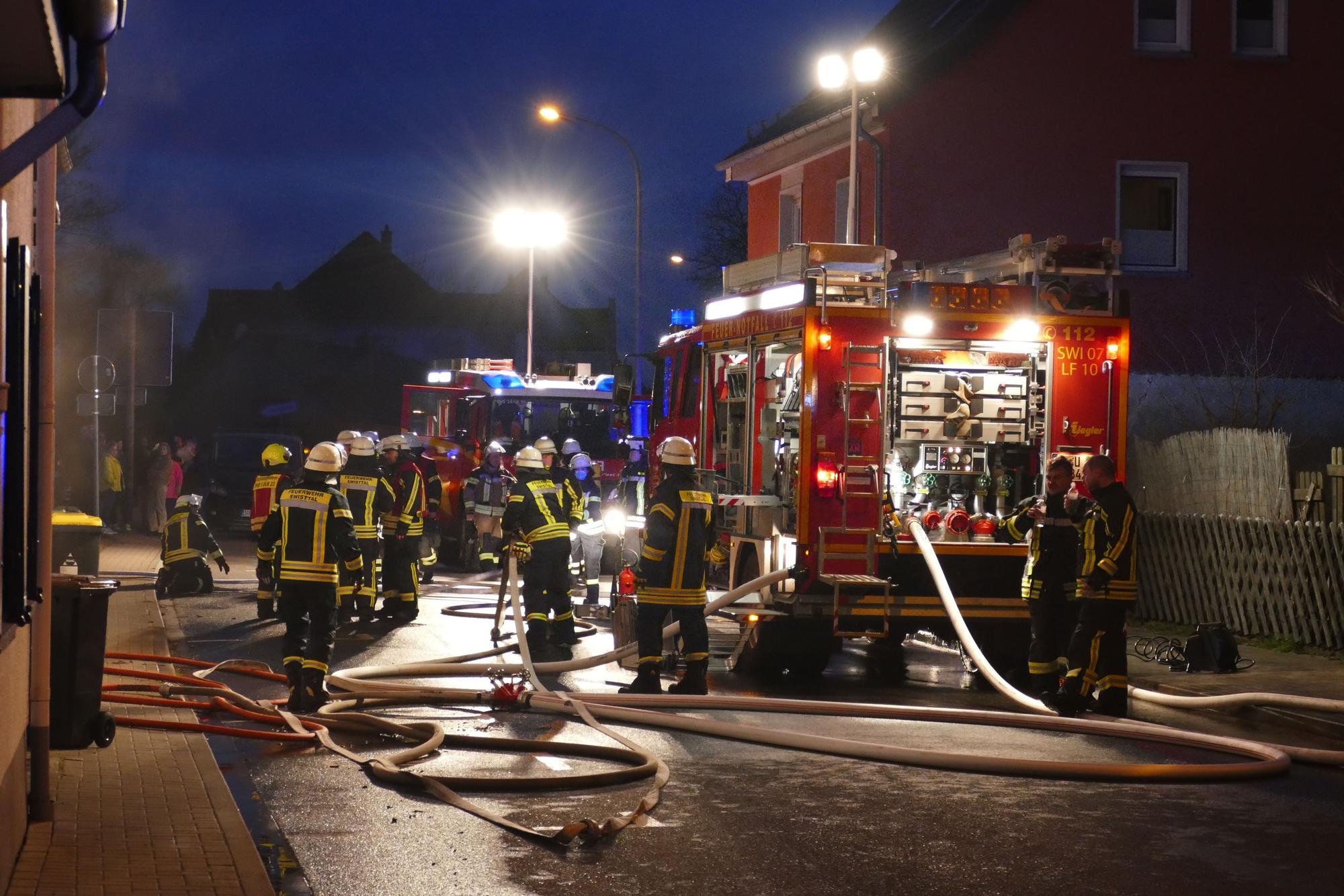 Feuerwehrautos und Feuerwehrleute auf einer Straße.