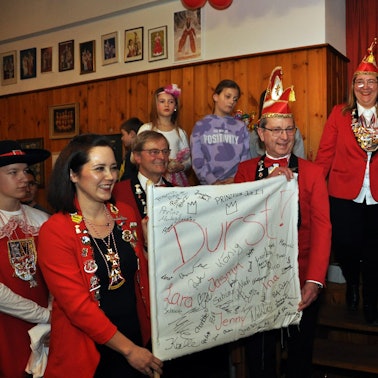 Einige Karnevalisten in roten Jacken halten eine weiße Fahne in der Hand, auf der „Durst!“ steht und auf der zahlreiche Unterschriften sind. Bürgermeister Hermann-Josef Esser hält im Hintergrund eine Rede.