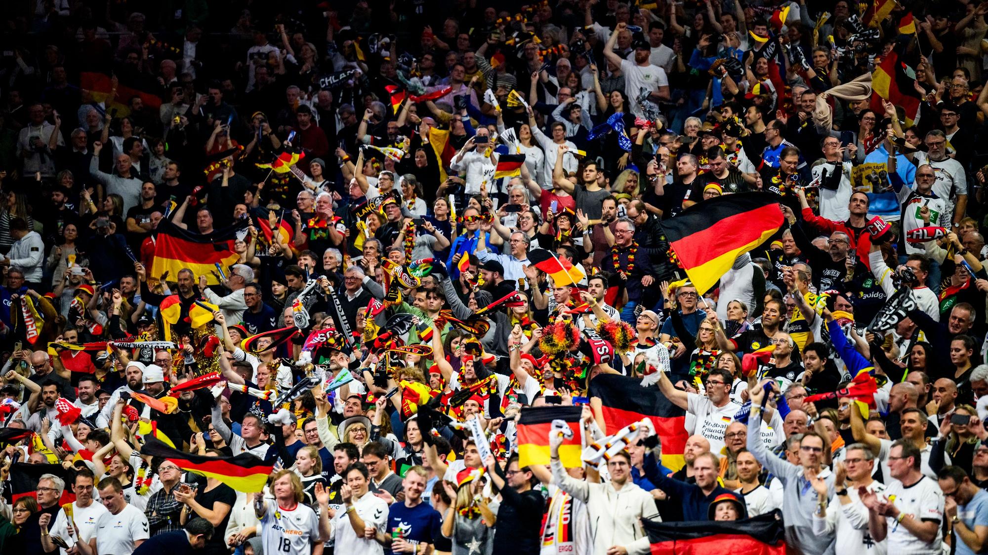 Deutsche Fans jubeln während eines Spiels mit Fahnen in der Lanxess Arena.