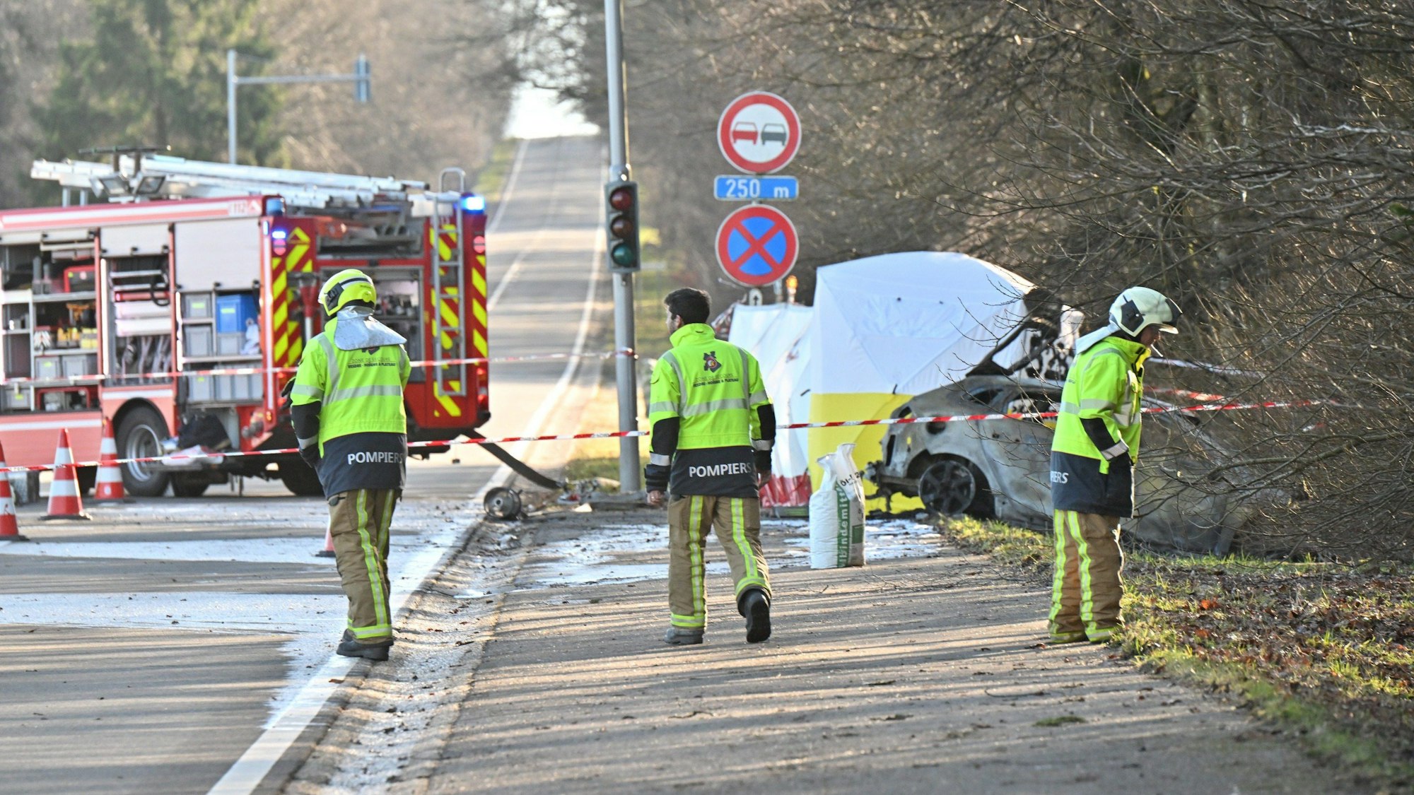 Rettungskräfte des belgischen Notfalldienstes sichern die Absturzstelle eines Kleinflugzeugs im belgischen Spa ab. Zwei Deutsche waren mit ihrer Maschine in ein parkendes Auto auf einer Landstraße geflogen.