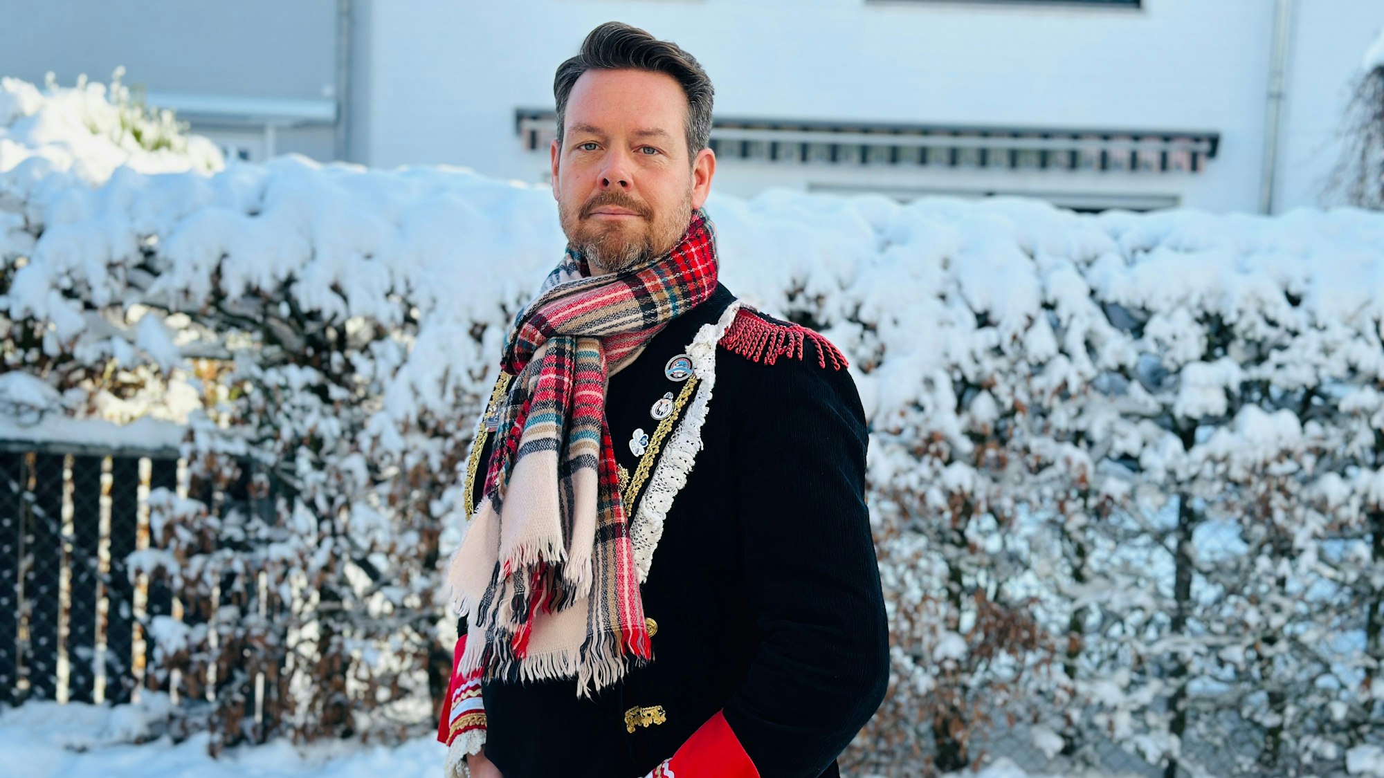 Der Zugleiter steht vor einer Hecke.