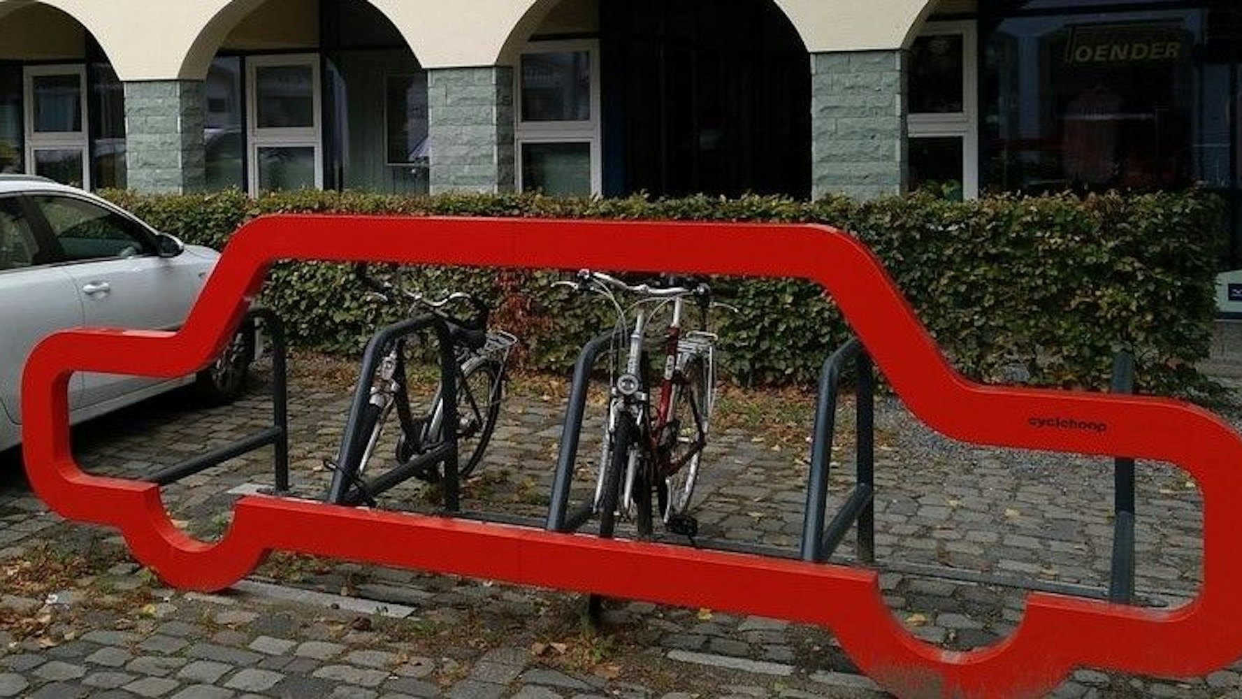 Neben einem Auto parken Fahrräder.