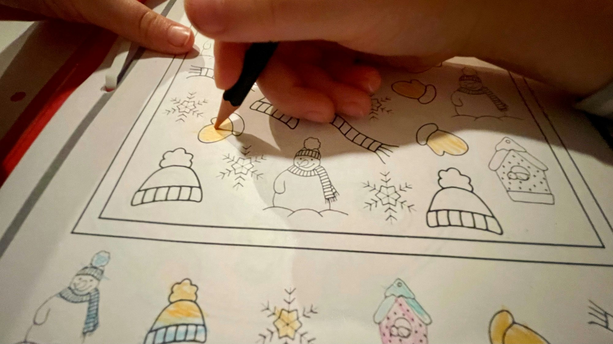 Das Bild zeigt die Hände eines Kindergartenkindes, das im Vorschulheft Bilder ausmalt.